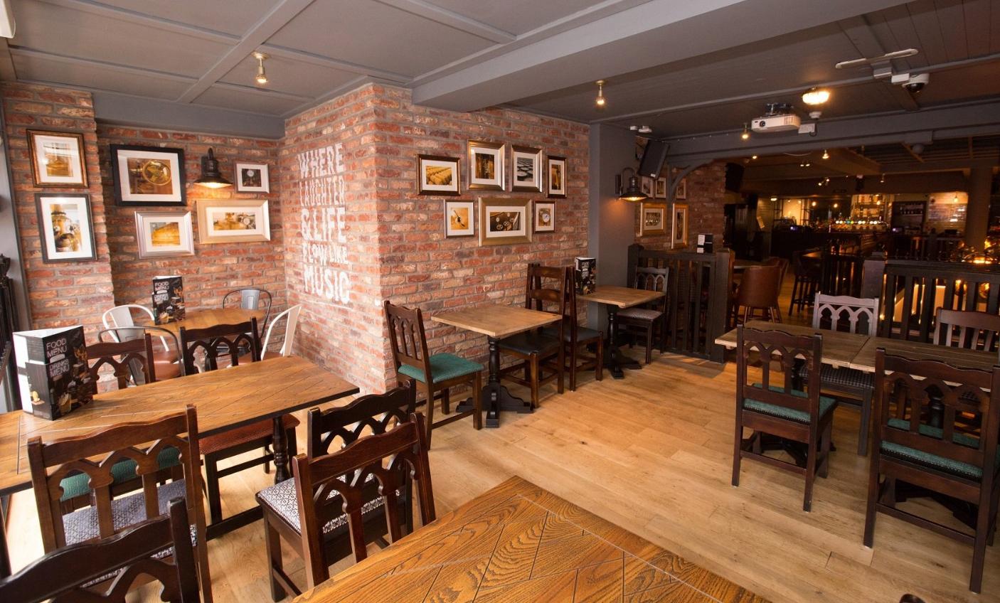 An event space in a pub with exposed brick walls, wooden tables, framed artwork, and ambient lighting at O'Neill's Wardour Street.