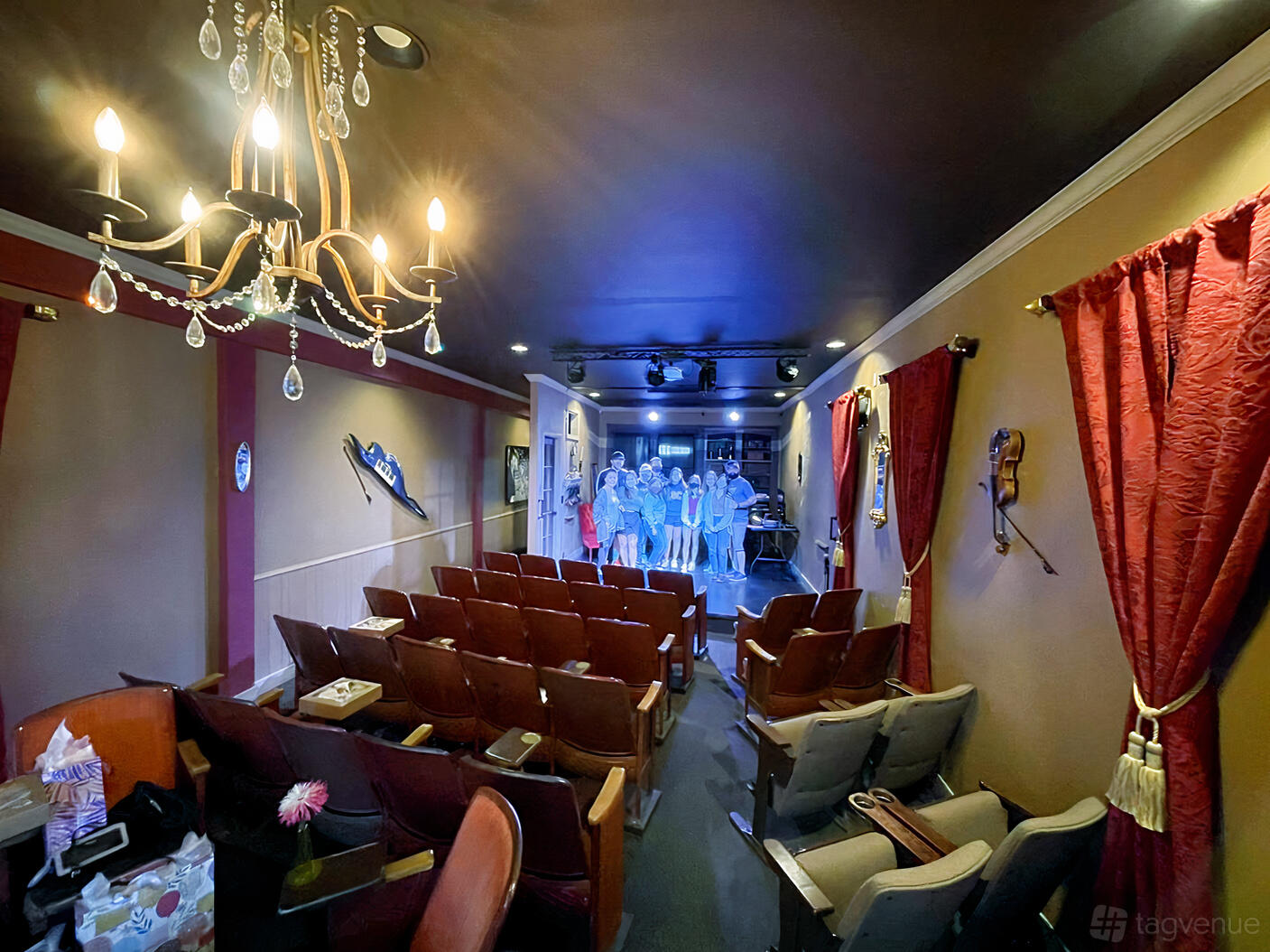 An event venue with red velvet curtains, vintage theater seats, and a chandelier at The Aurora Theater.