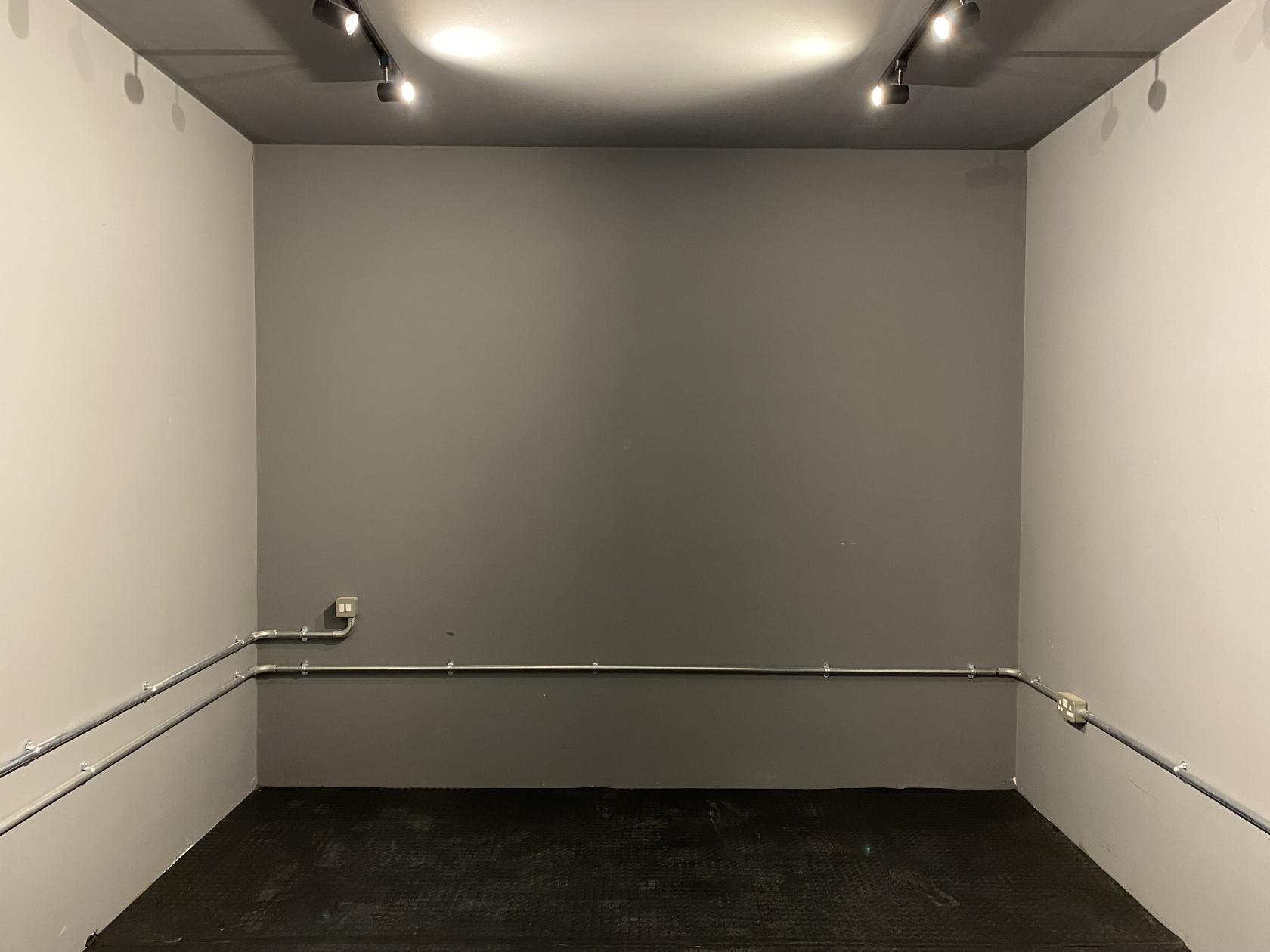 An event venue with grey walls, exposed metal conduit, and track lighting at FOLD Studio.