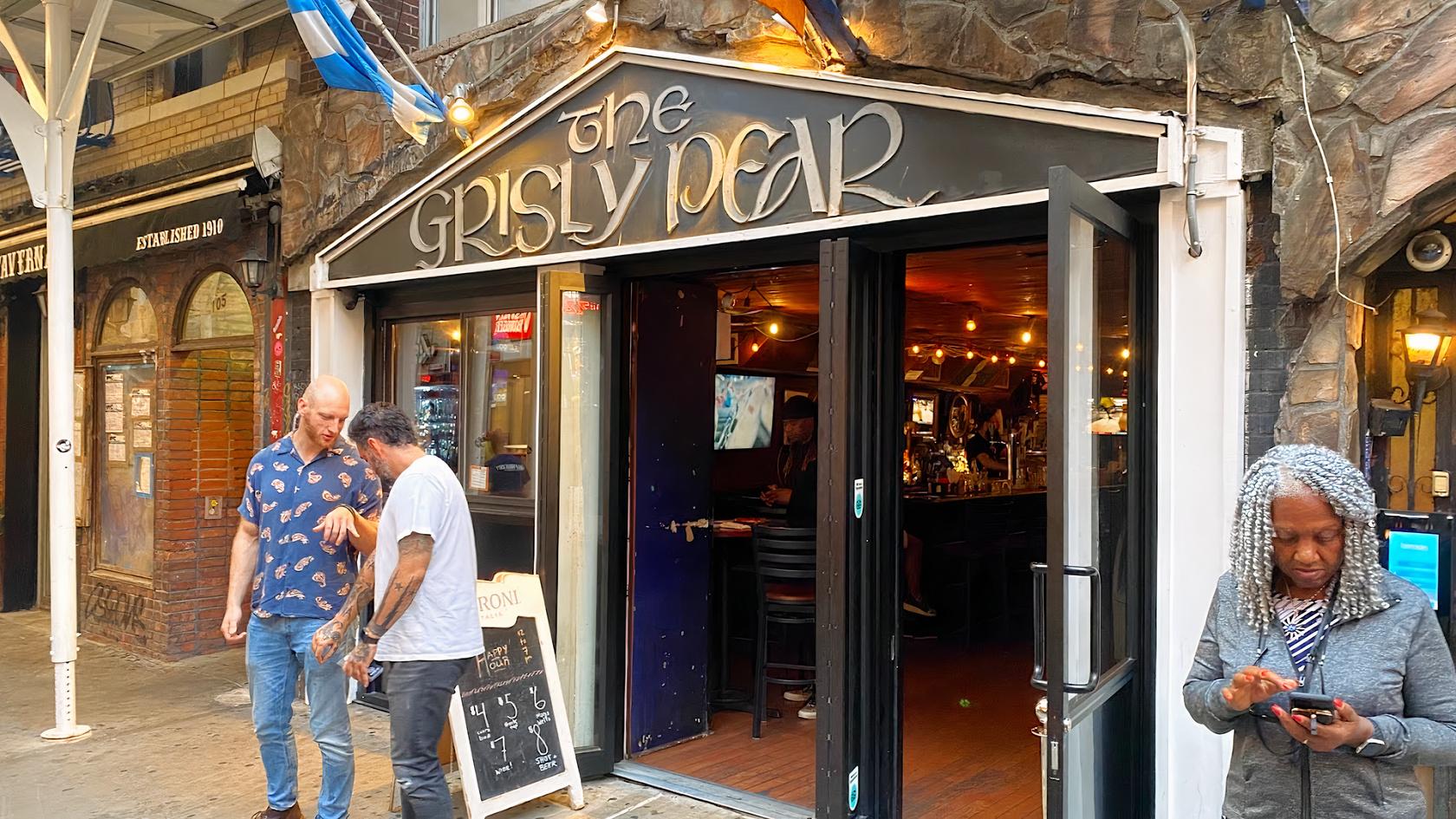 A pub with an open entrance, string lights, exposed brick walls, and bar seating at The Grisly Pear Greenwich Village