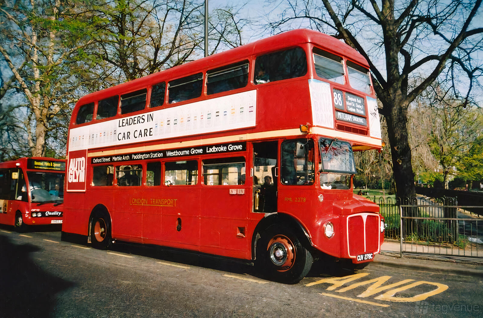 A double-decker red party bus parked on a city street with large windows at The Red Bus Bistro Glasgow.