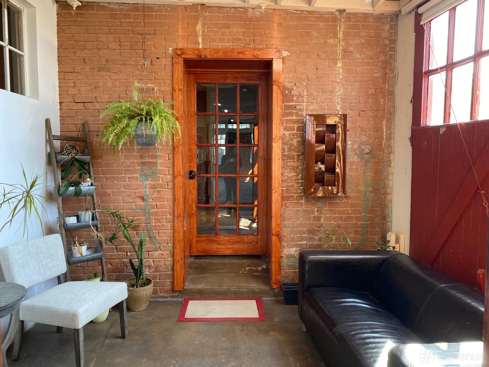 An event venue with exposed brick walls, a wooden-framed glass door, and leather seating at 2700 Swiss Event Space.