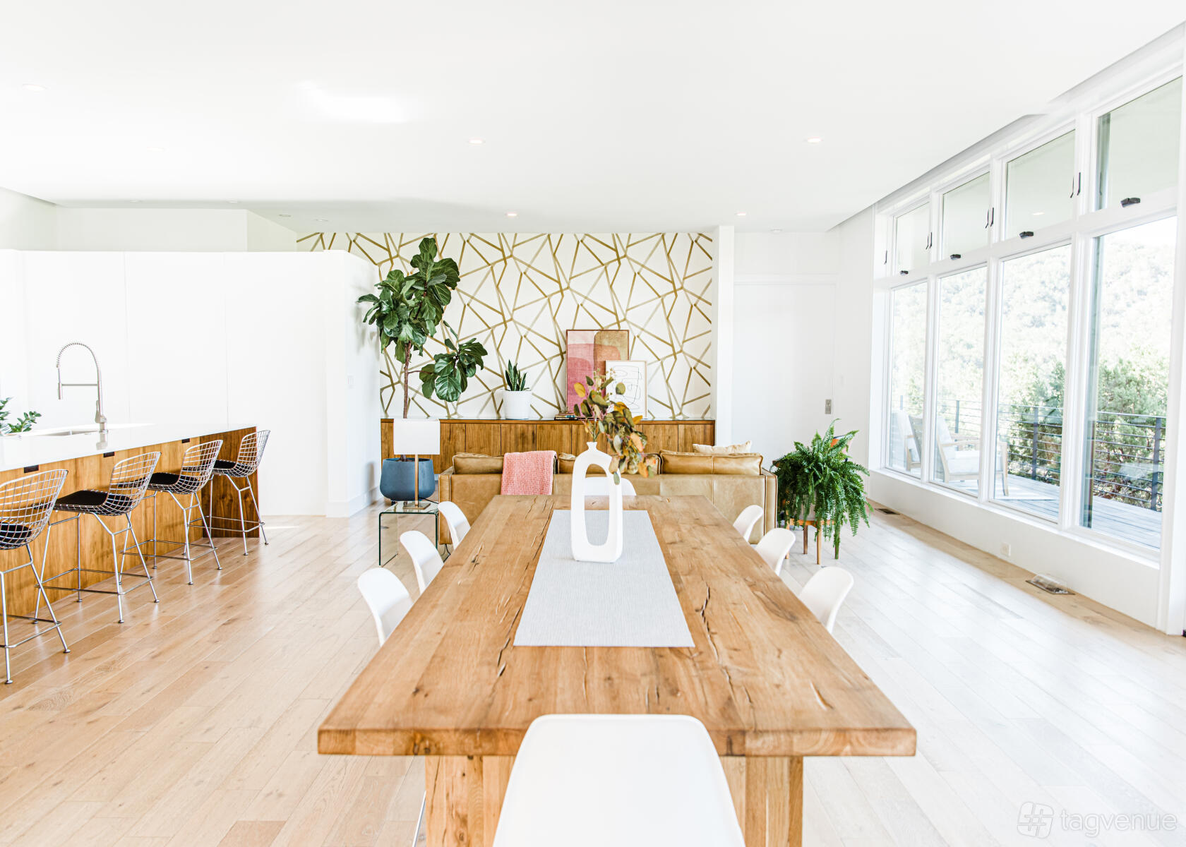 An open-plan country house with light wood floors, large windows, and a wooden dining table at Hill Country Home ATX.