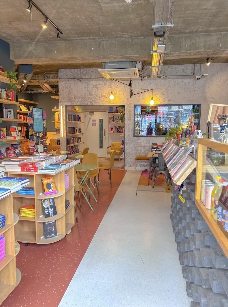An event venue with bookshelves, round tables with chairs, and pendant lighting at The Common Press.