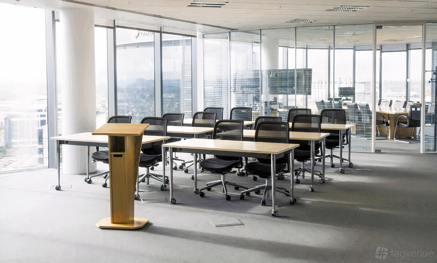 A training room with glass walls, movable desks, black mesh chairs, and a wooden lectern at Paragon House.