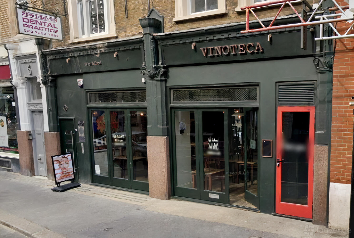 A restaurant with a dark green facade, large front windows, and glass doors at Vinoteca Farringdon.
