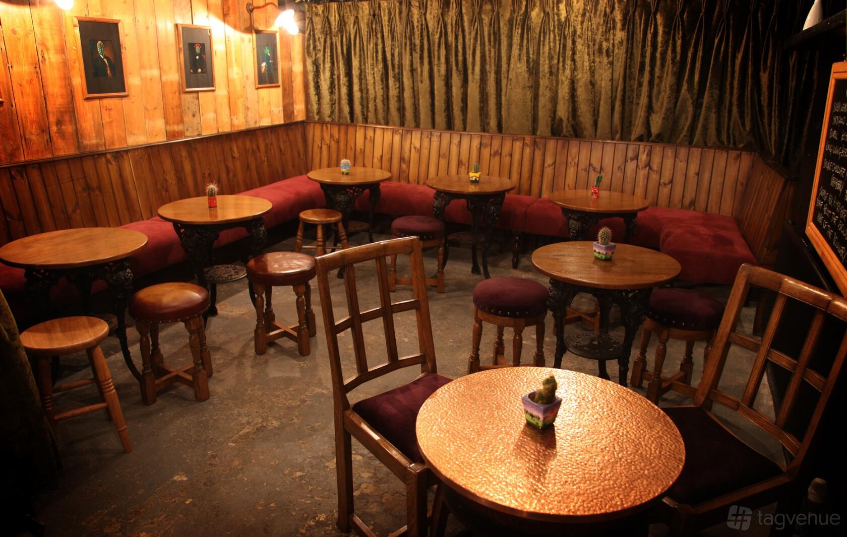 A pub with round wooden tables, cushioned bench seating, and wood-paneled walls at The Mitre Lancaster Gate.
