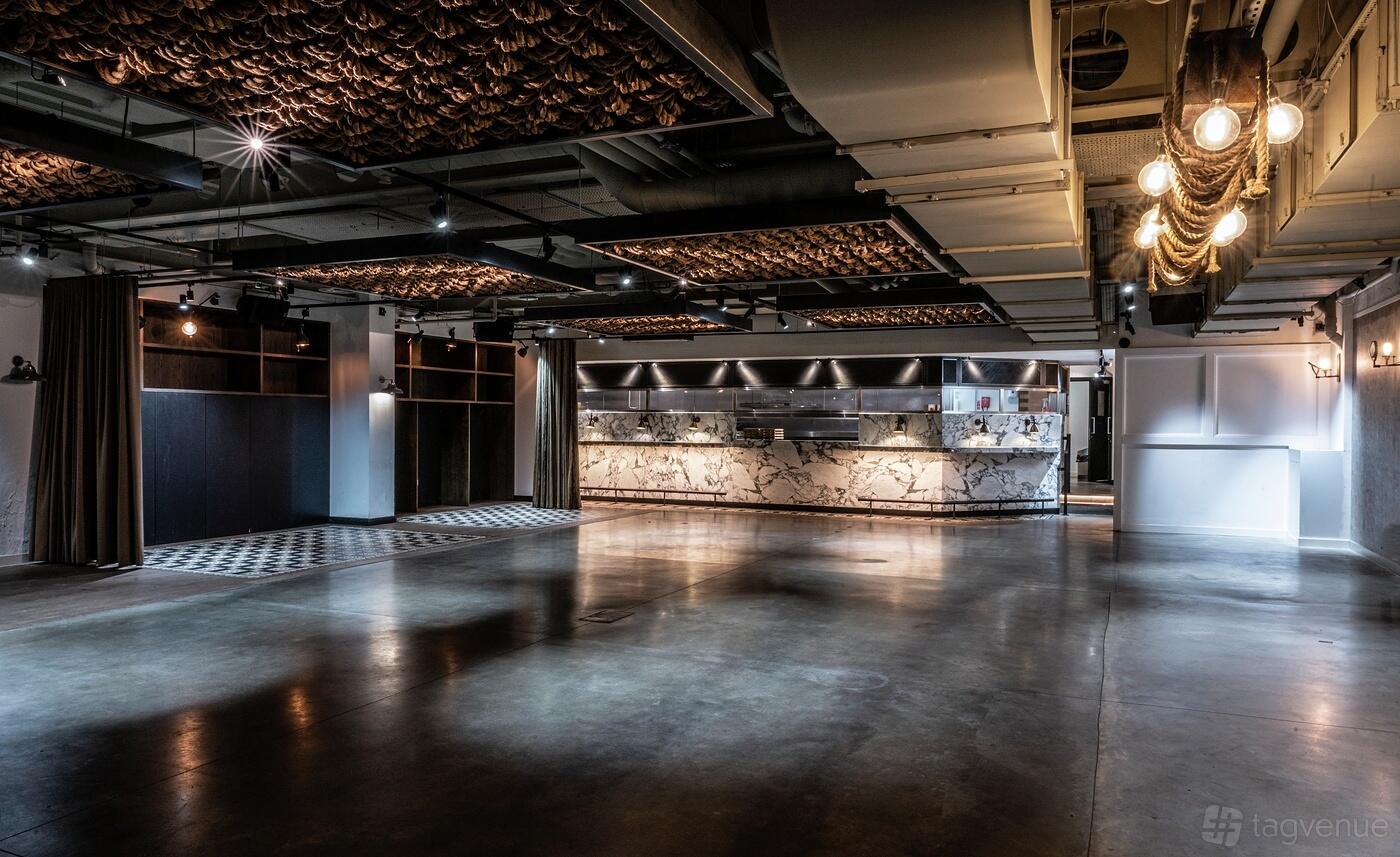 An event space in a restaurant with polished concrete floors, marble-fronted bar, and exposed ceiling at Bread Street Kitchen, The City.