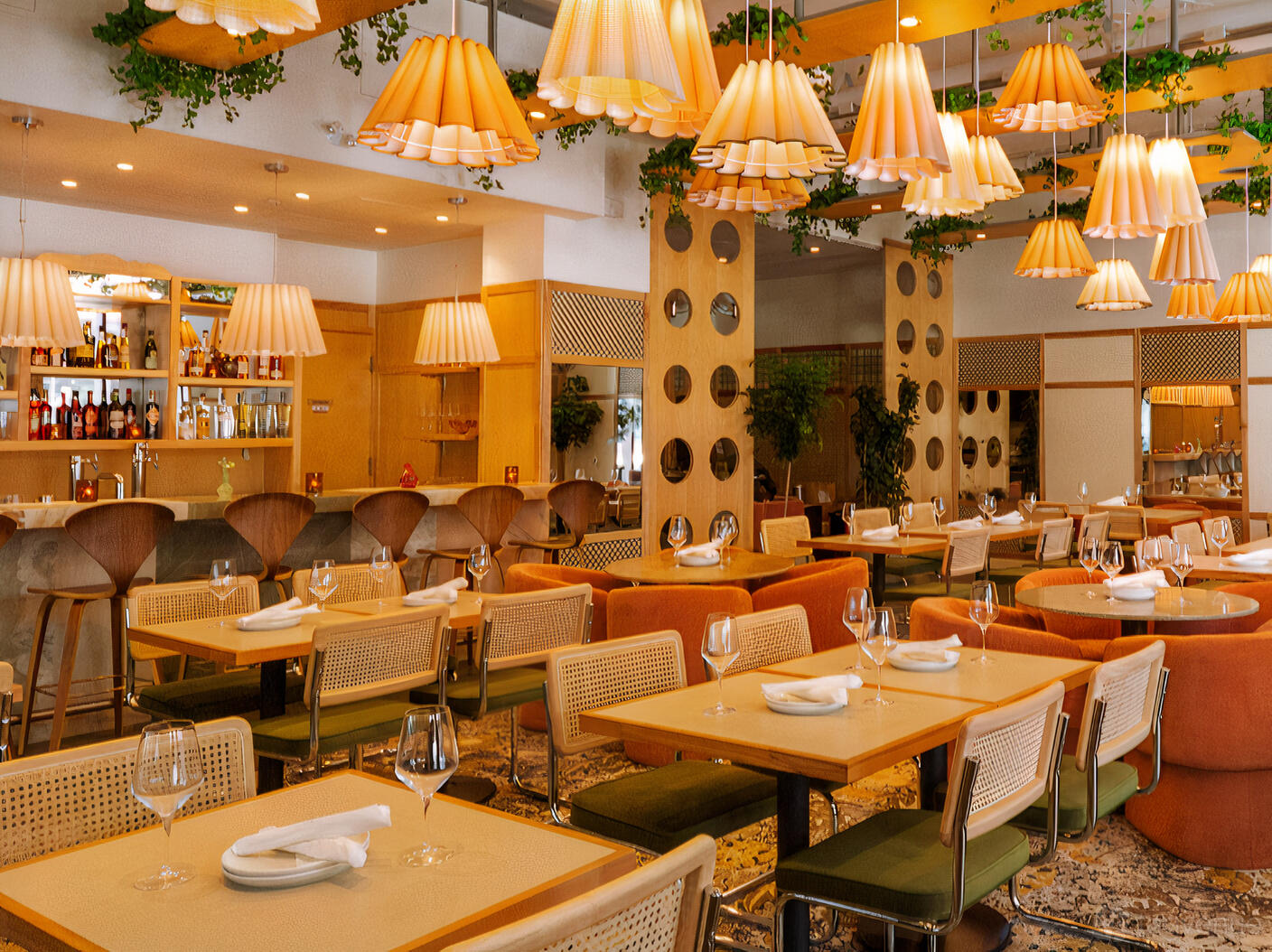A restaurant with rattan chairs, square tables set with glassware, and pendant lamps at Cafe Zuzu.