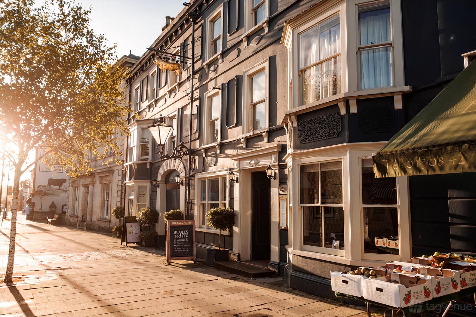 A hotel with a historic facade, large bay windows, and sidewalk market stalls at The Bull Hotel Dorset.