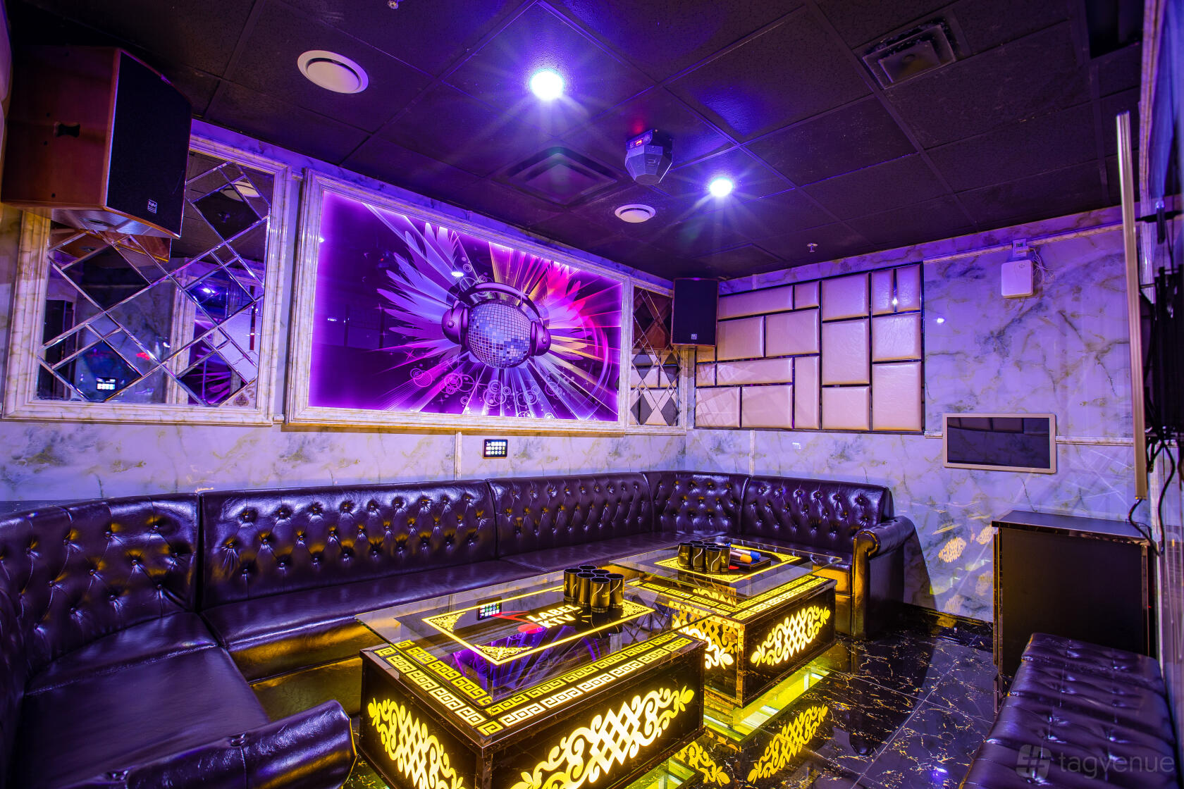 A karaoke bar with leather banquette seating, mirrored walls, and neon backlit decor at Label KTV.
