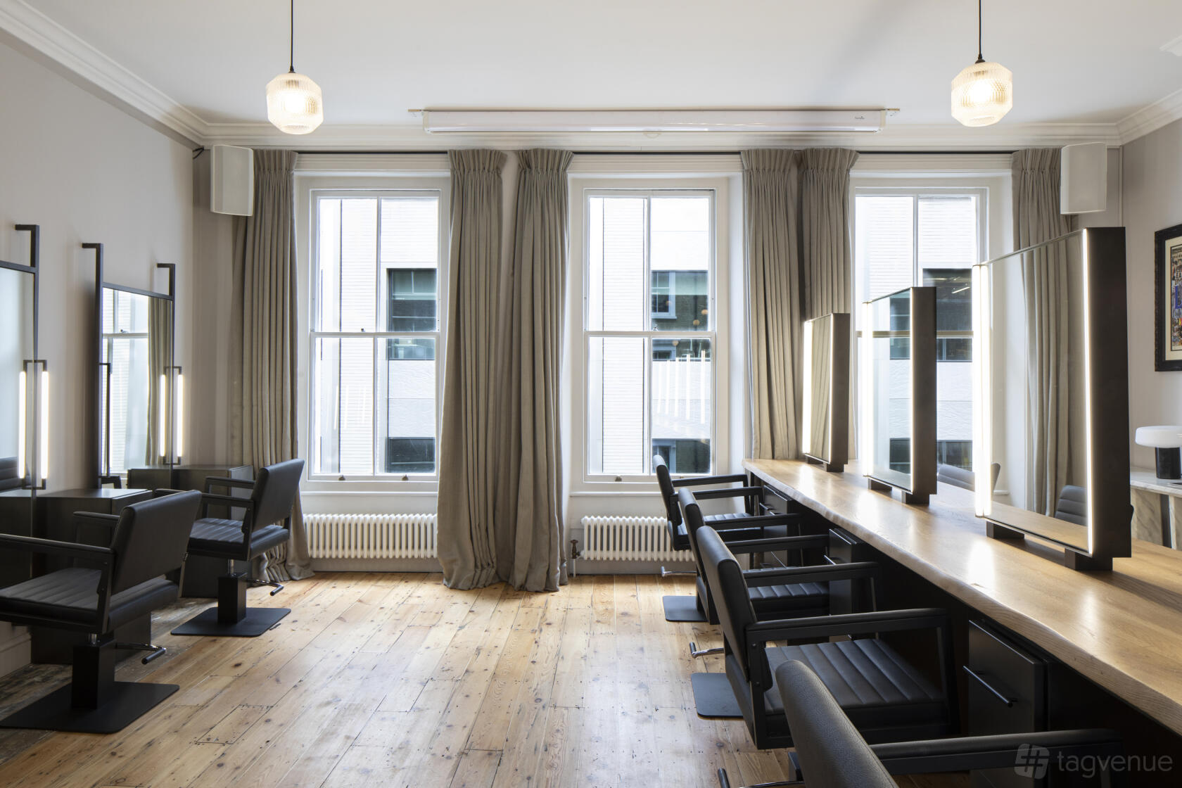 An event space in a historic building with tall windows, wooden floors, and salon-style chairs at Electric Space.
