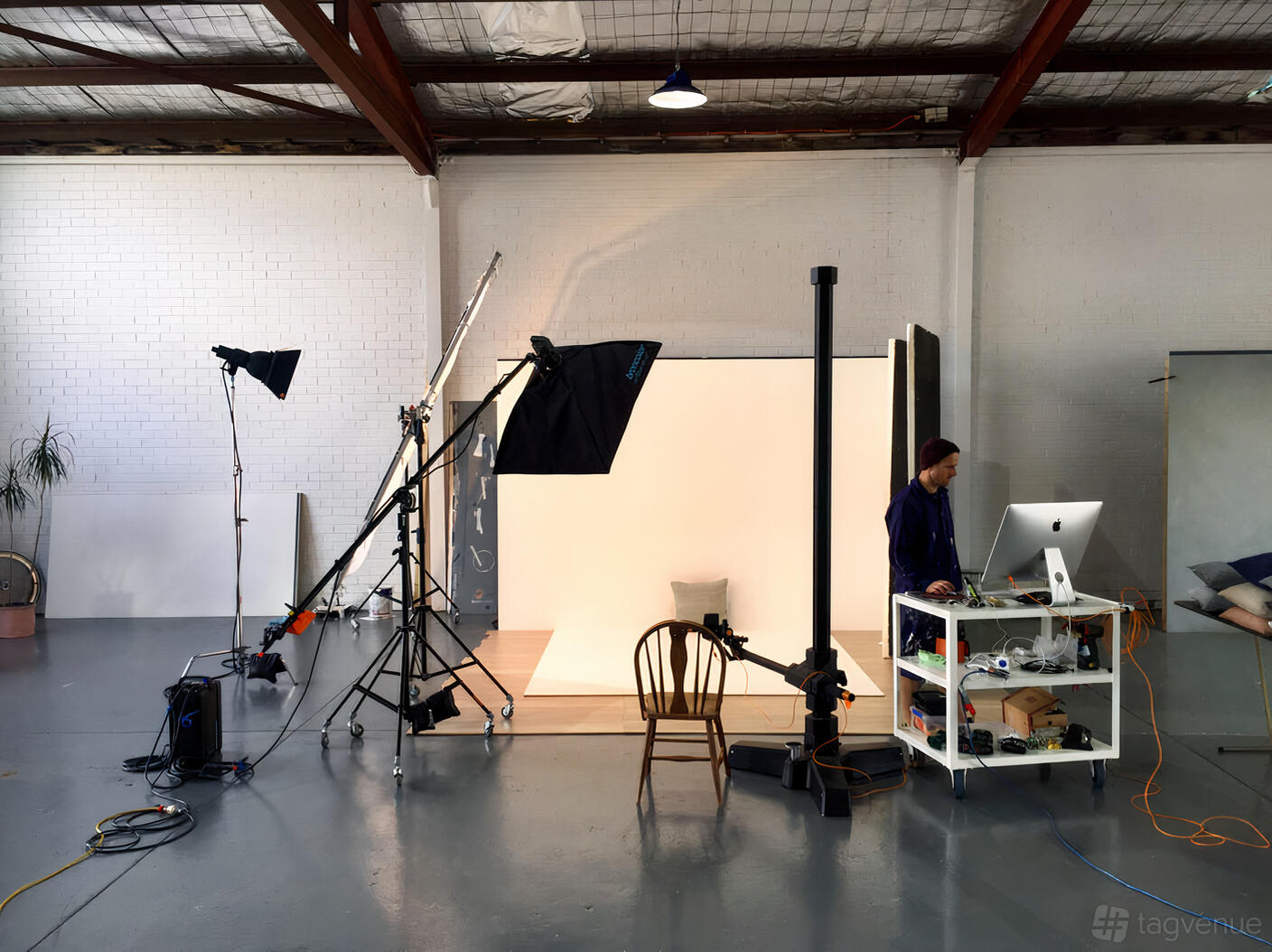 A photo studio with white walls, a seamless backdrop, studio lights, and camera equipment at Lampoluce Photography + Studios.