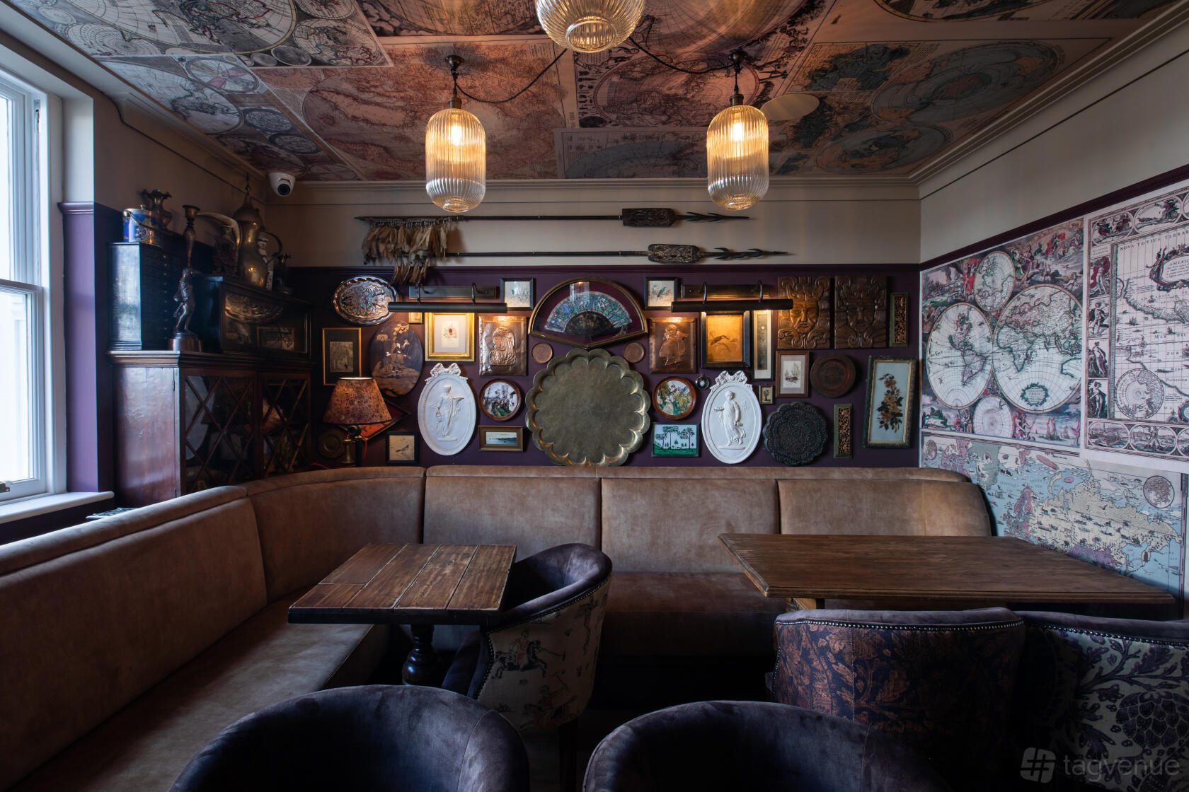 A pub dining room with vintage maps on the ceiling, framed art on the walls, and leather banquette seating at Enderby House.