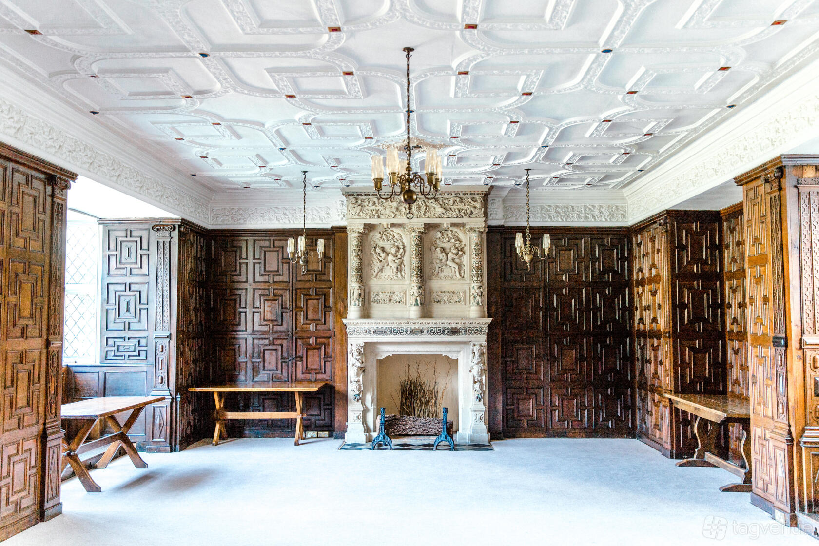 An event venue with dark wood paneling, ornate fireplace, and decorative plaster ceiling at Rothamsted Manor.