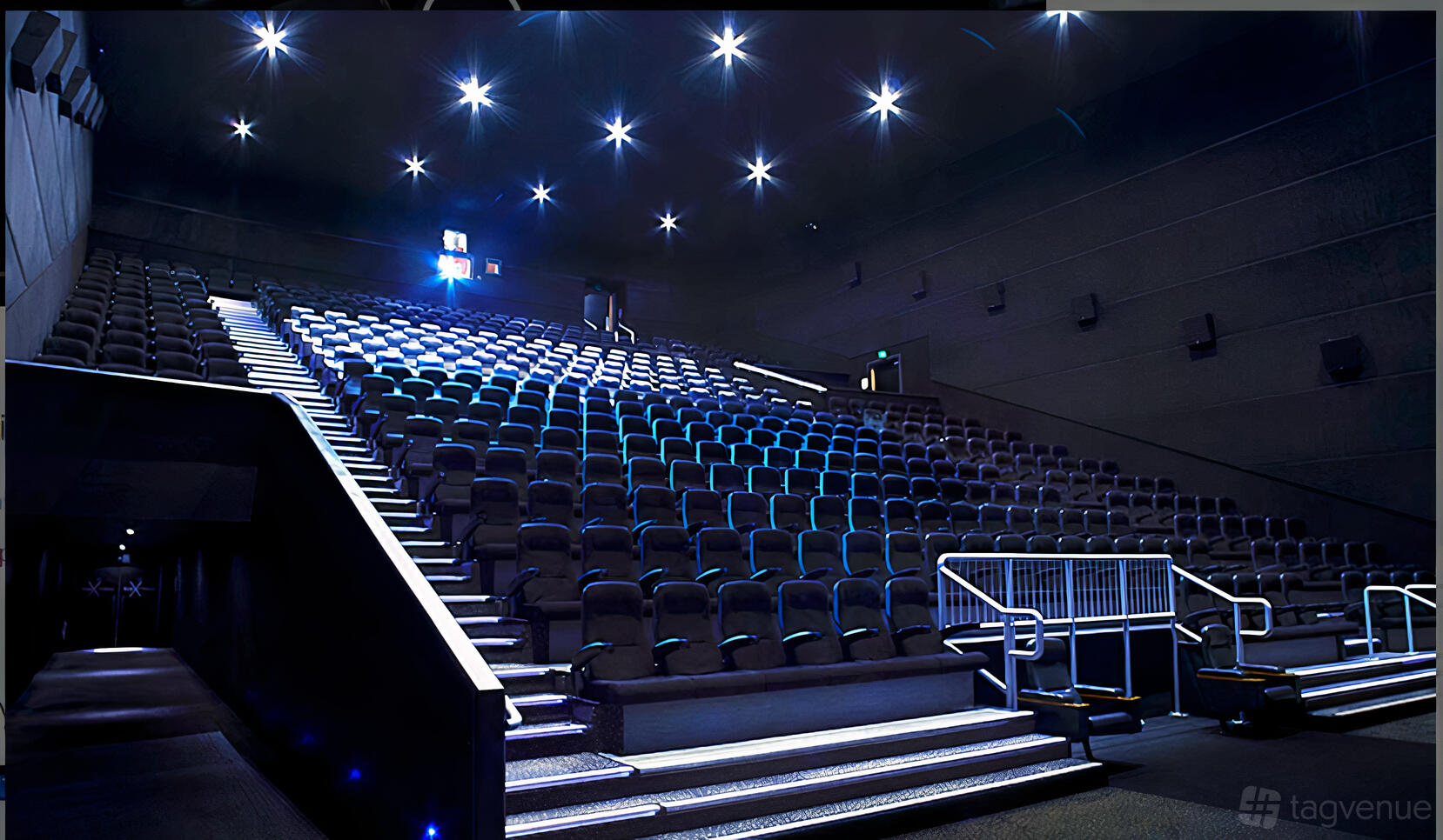 A cinema auditorium with tiered seating, illuminated aisle lights, and dark walls at Vue Birkenhead (Liverpool)
