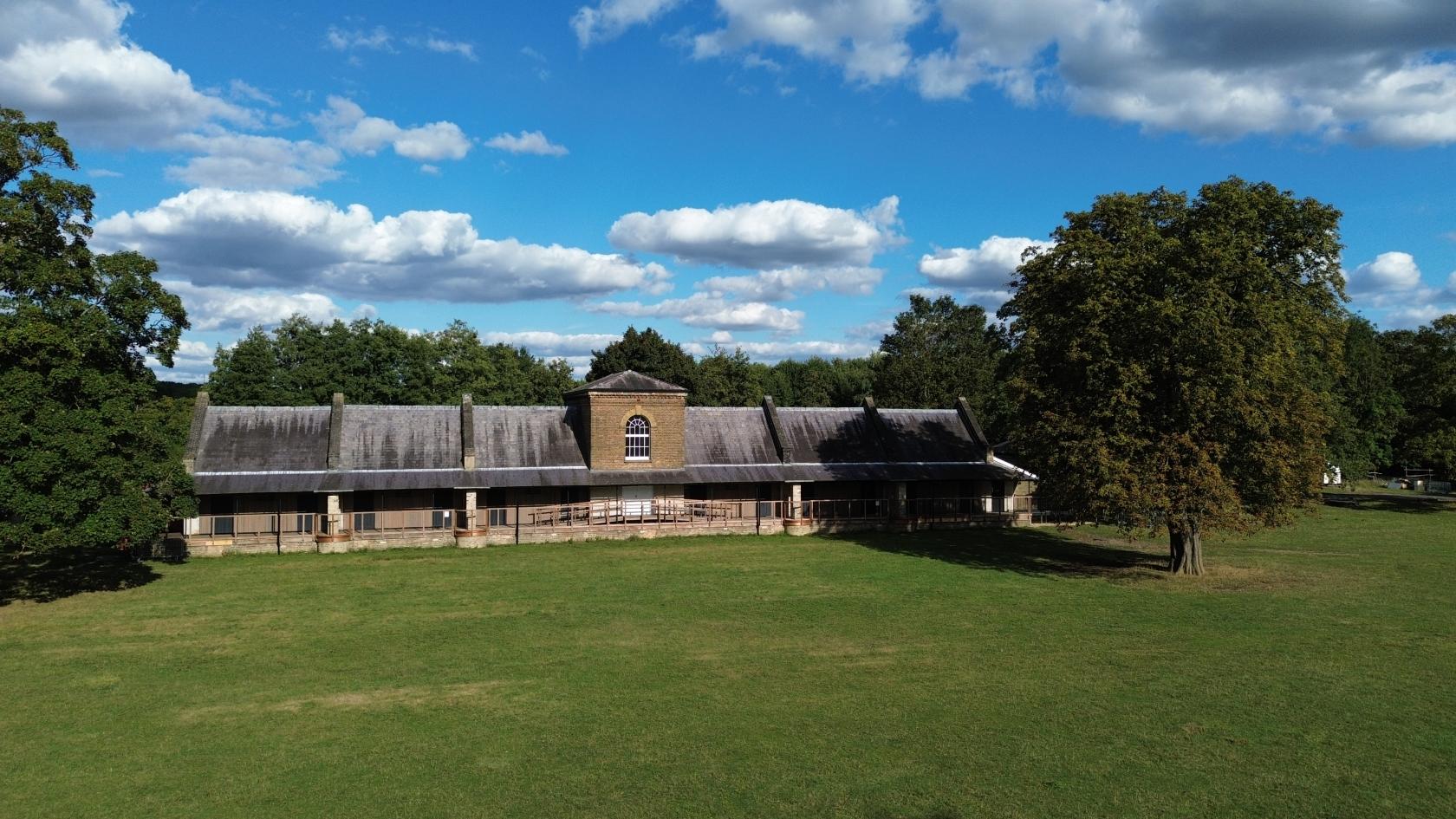 An outdoor event lawn with a historic building and large tree at Royal Gunpowder Mills
