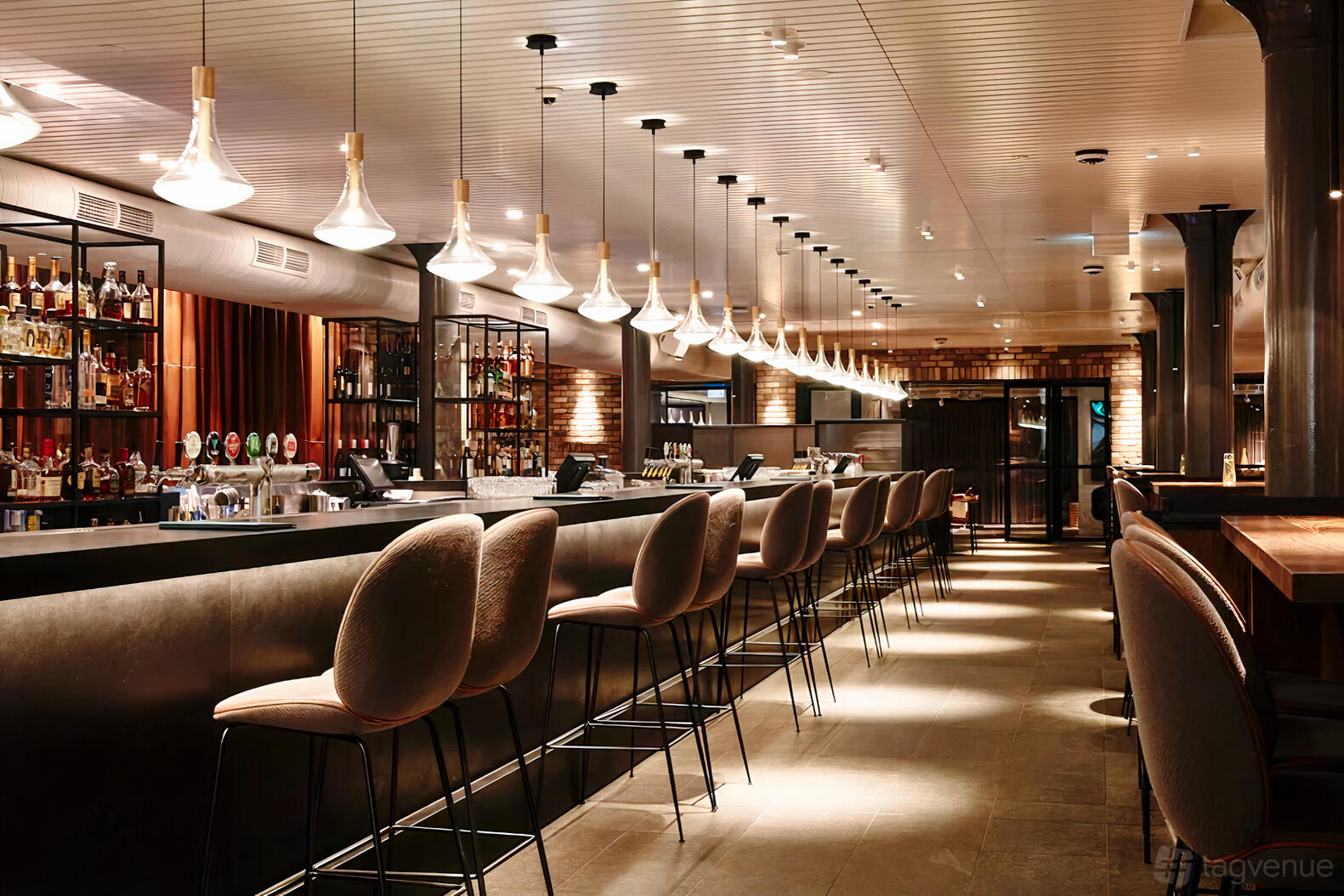 A restaurant with a long marble-topped bar, modern pendant lights, and upholstered bar stools at The George on Collins.