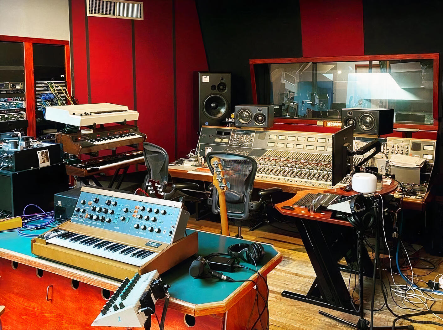 A recording studio with audio mixers, synthesizers, and soundproofed walls at Mission Sound.