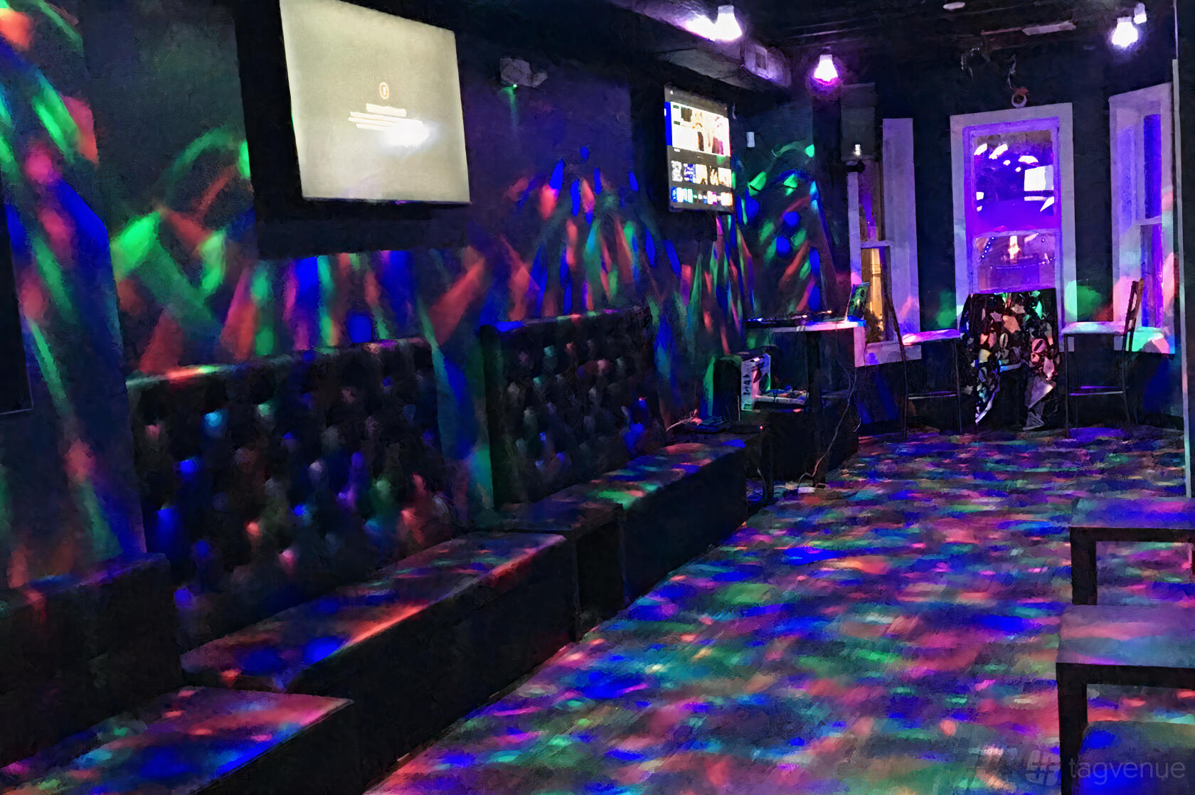 An event space in a nightclub with tufted black leather seating, LED dance floor lights, and wall-mounted screens at Ocean Lounge.