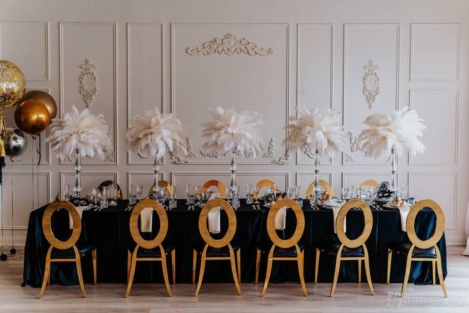 An event space with gold chairs, a long banquet table, and tall feather centerpieces at Espace Studio.