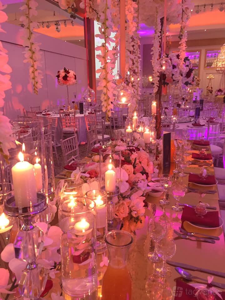 A function room with tall candle centerpieces, pink floral arrangements, and round banquet tables at The Old Street Gallery.