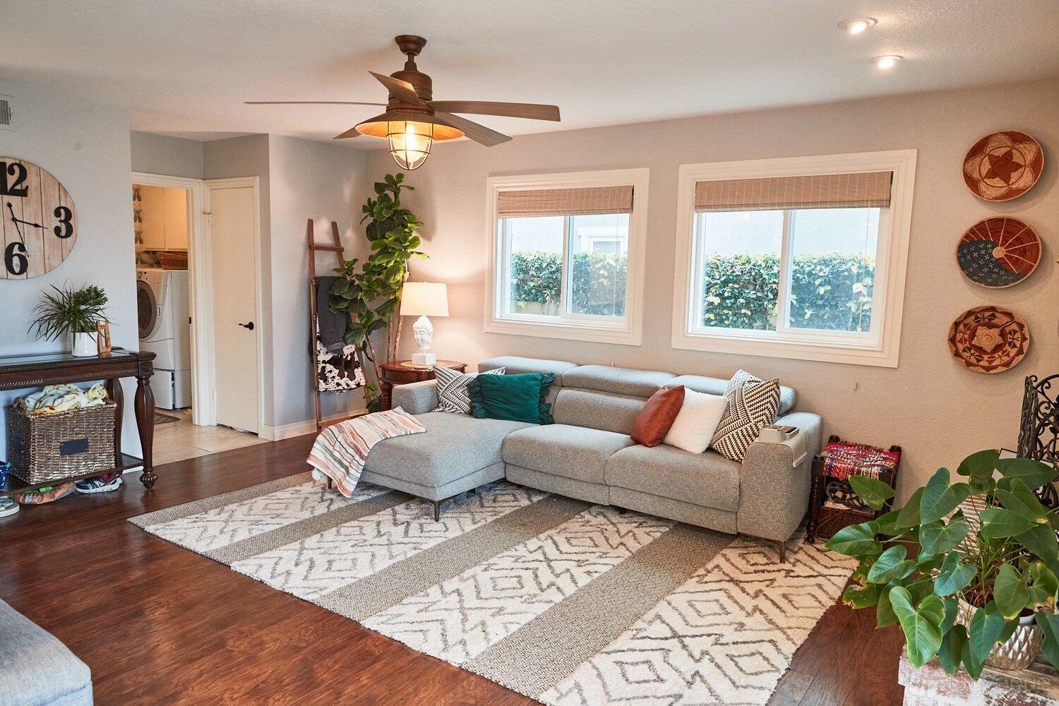 An apartment living room with a sectional sofa, area rug, wood floors, and large windows at Spacious and Bright 2-Story Home.