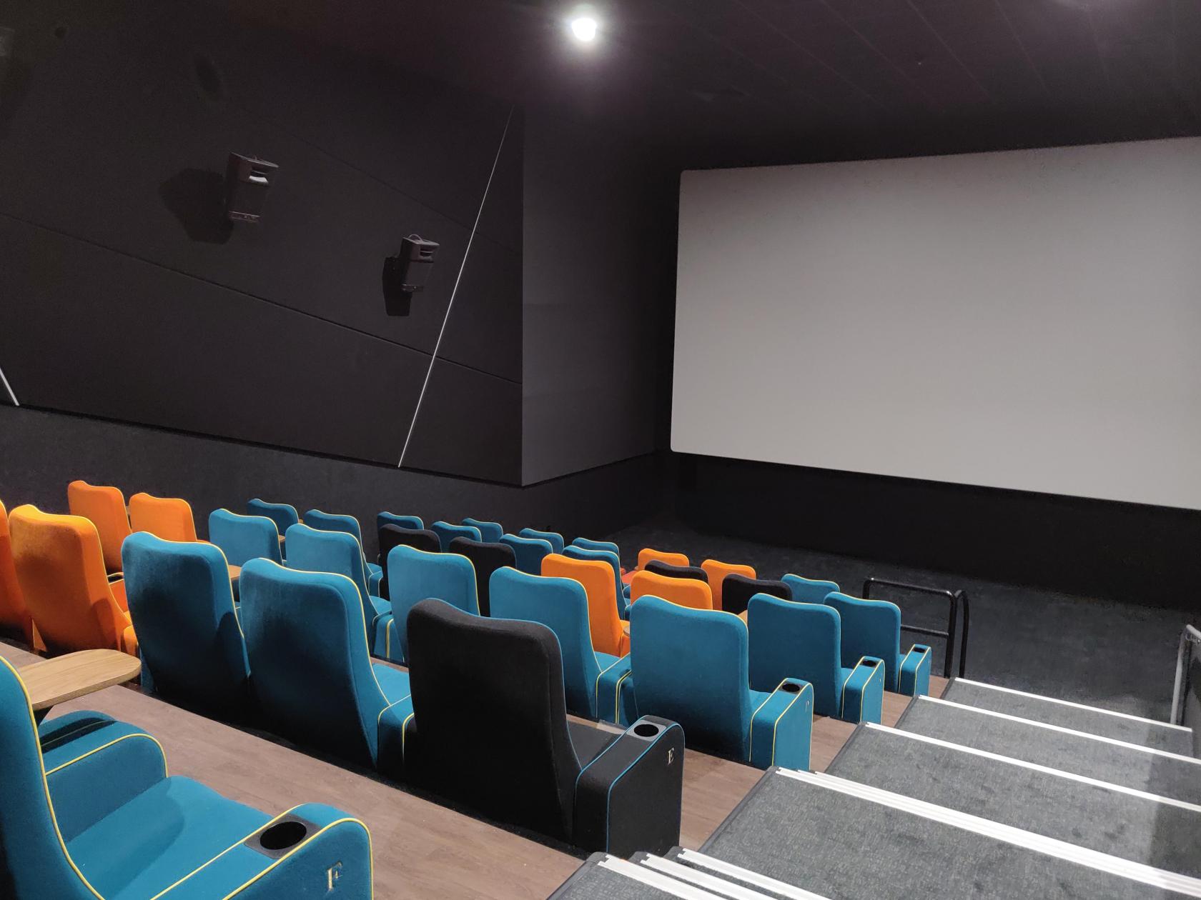 A cinema auditorium with tiered rows of colorful seats facing a large projection screen at The Light Cinema - Bradford.