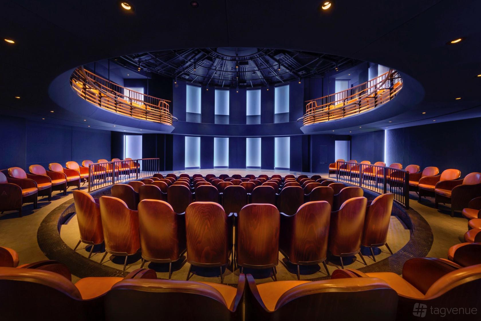 An auditorium with curved rows of red velvet seats and a wraparound balcony at Underbelly Boulevard.