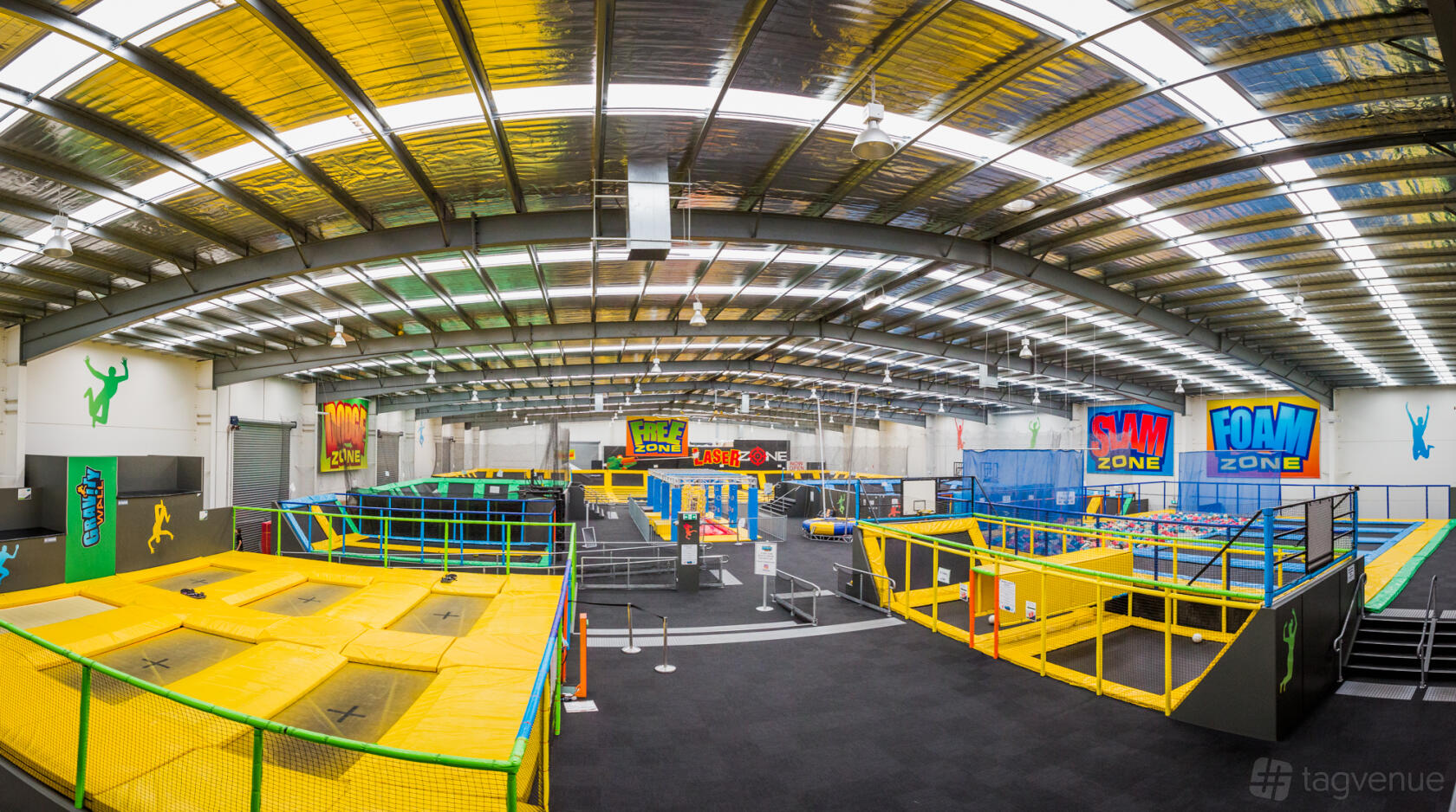 An indoor event venue with bright yellow trampolines, foam pits, and metal ceiling panels at Gravity Zone.