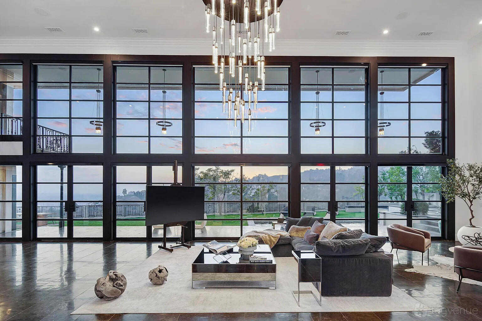 An apartment living area with floor-to-ceiling windows, a contemporary chandelier, and plush seating at Sophisticated Estate with Views.