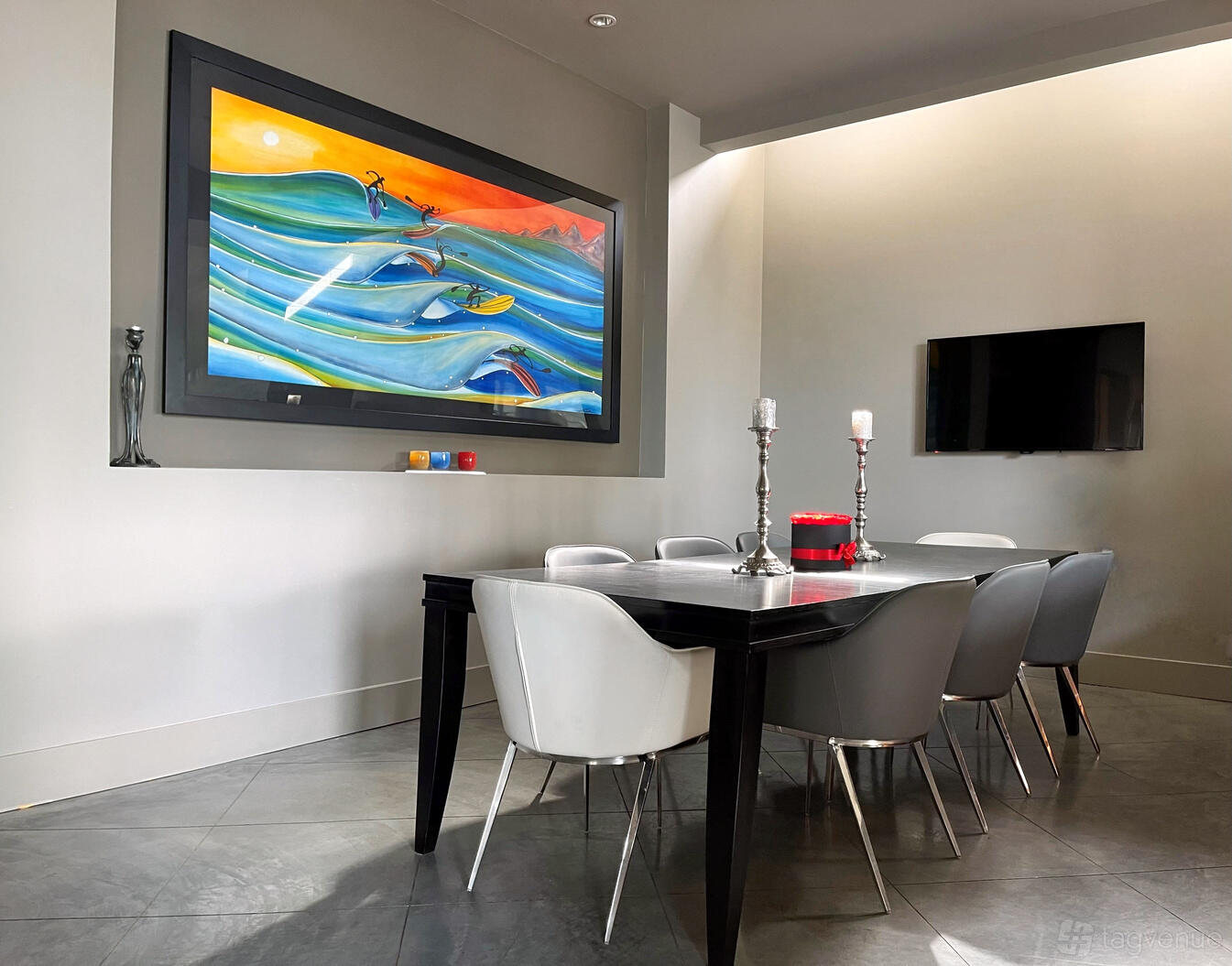 A house dining area with a dark rectangular table, modern chairs, and a colorful surfing painting at The Willow Vita.