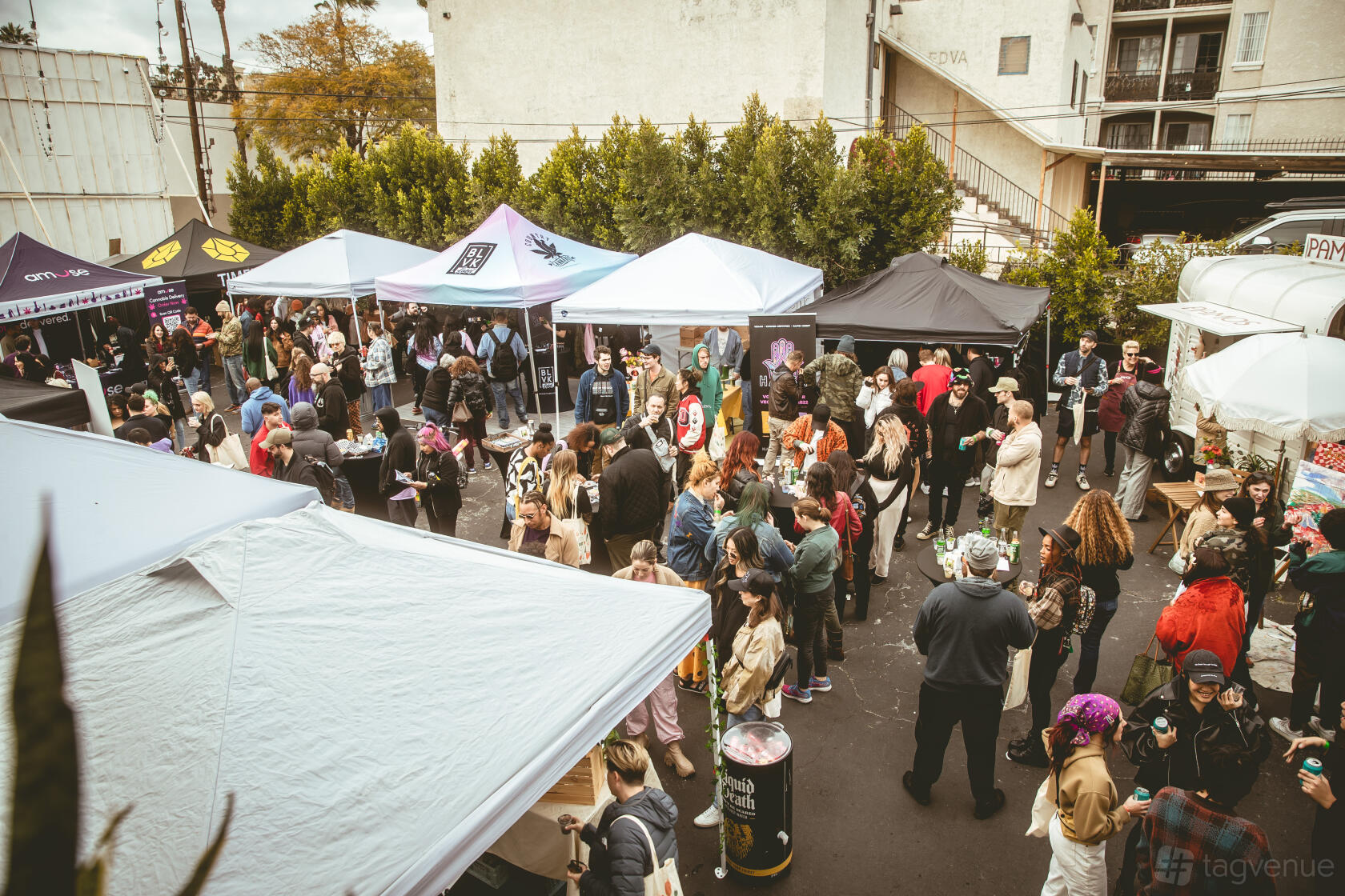 An outdoor event venue with pop-up tents, food stalls, and a crowd of guests at beTRUE Los Angeles.