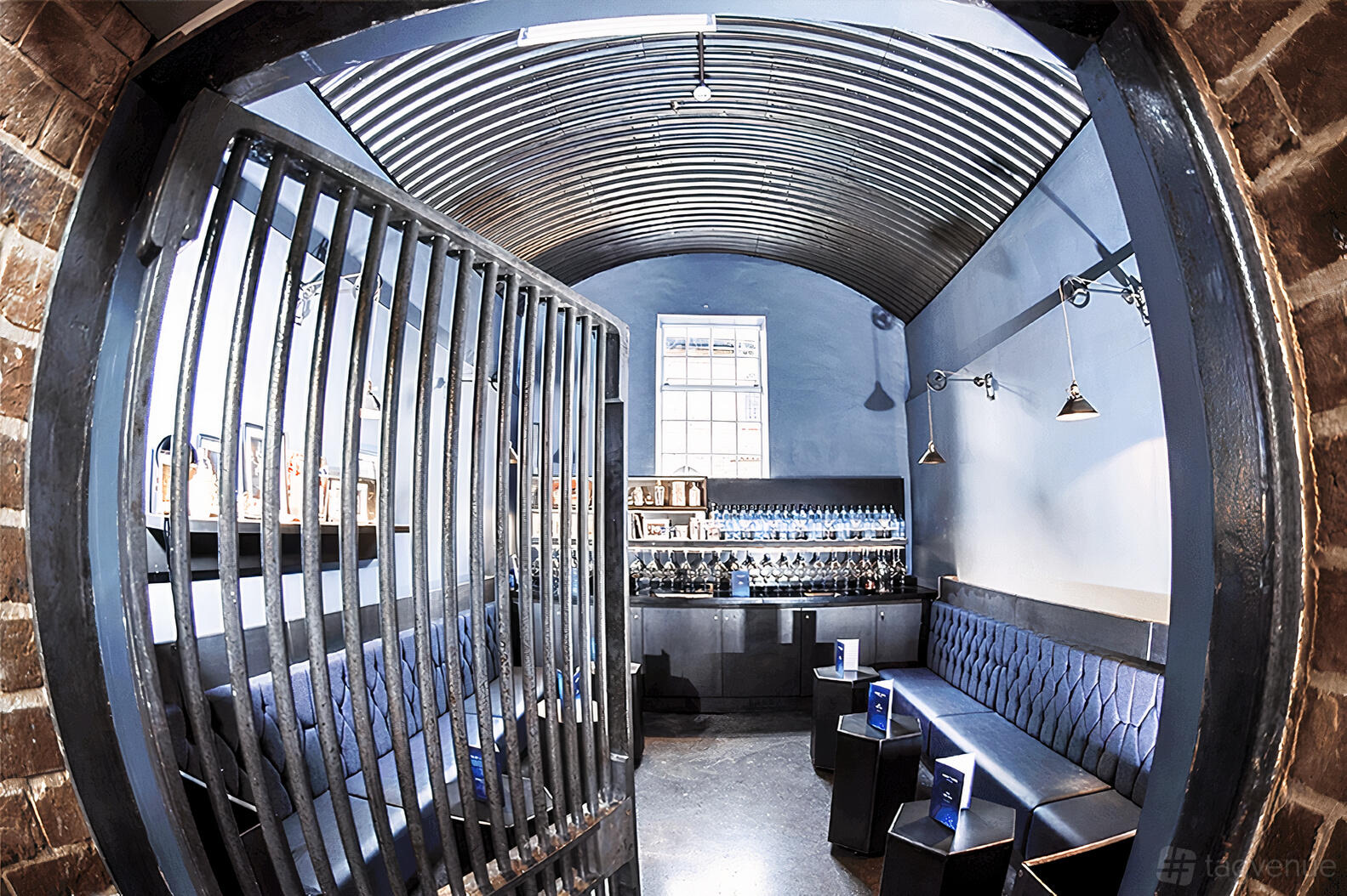 An intimate event space with exposed brick walls, vaulted ceiling, and navy tufted seating at Bombay Sapphire Distillery.