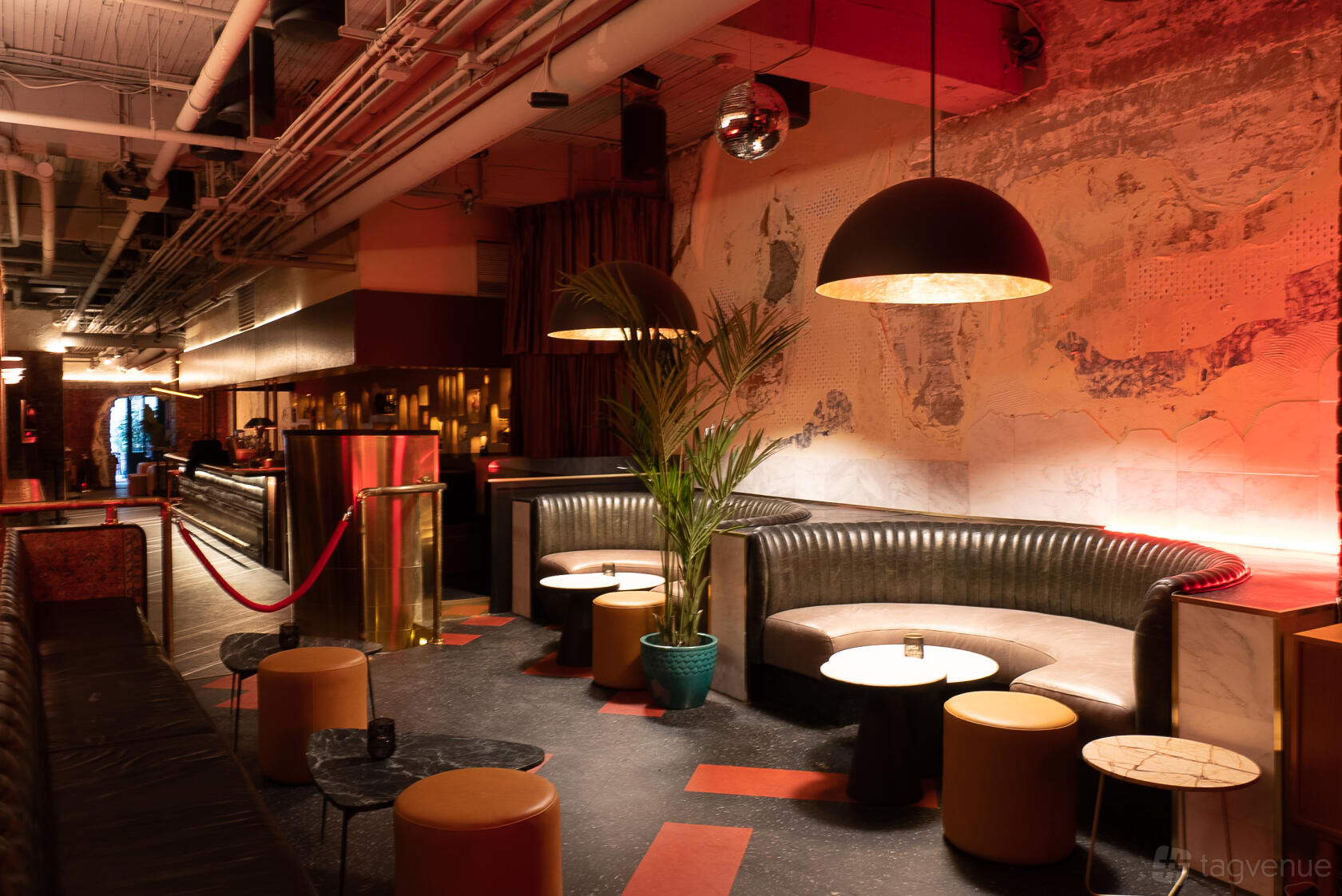 A lounge bar with curved leather banquettes, round tables, low stools, and warm lighting at Isabelle's Vancouver.