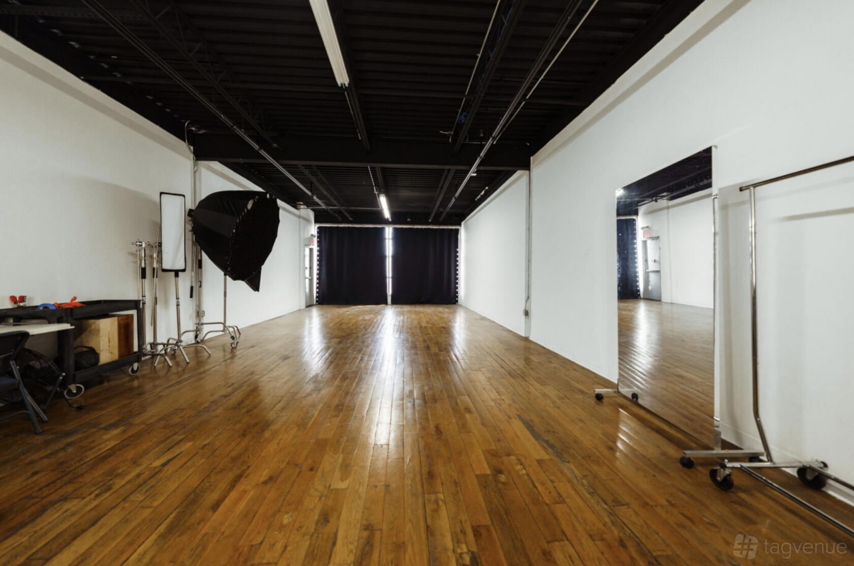 A photo studio with hardwood floors, large wall mirror, and black ceiling at Brooklyn Studios.