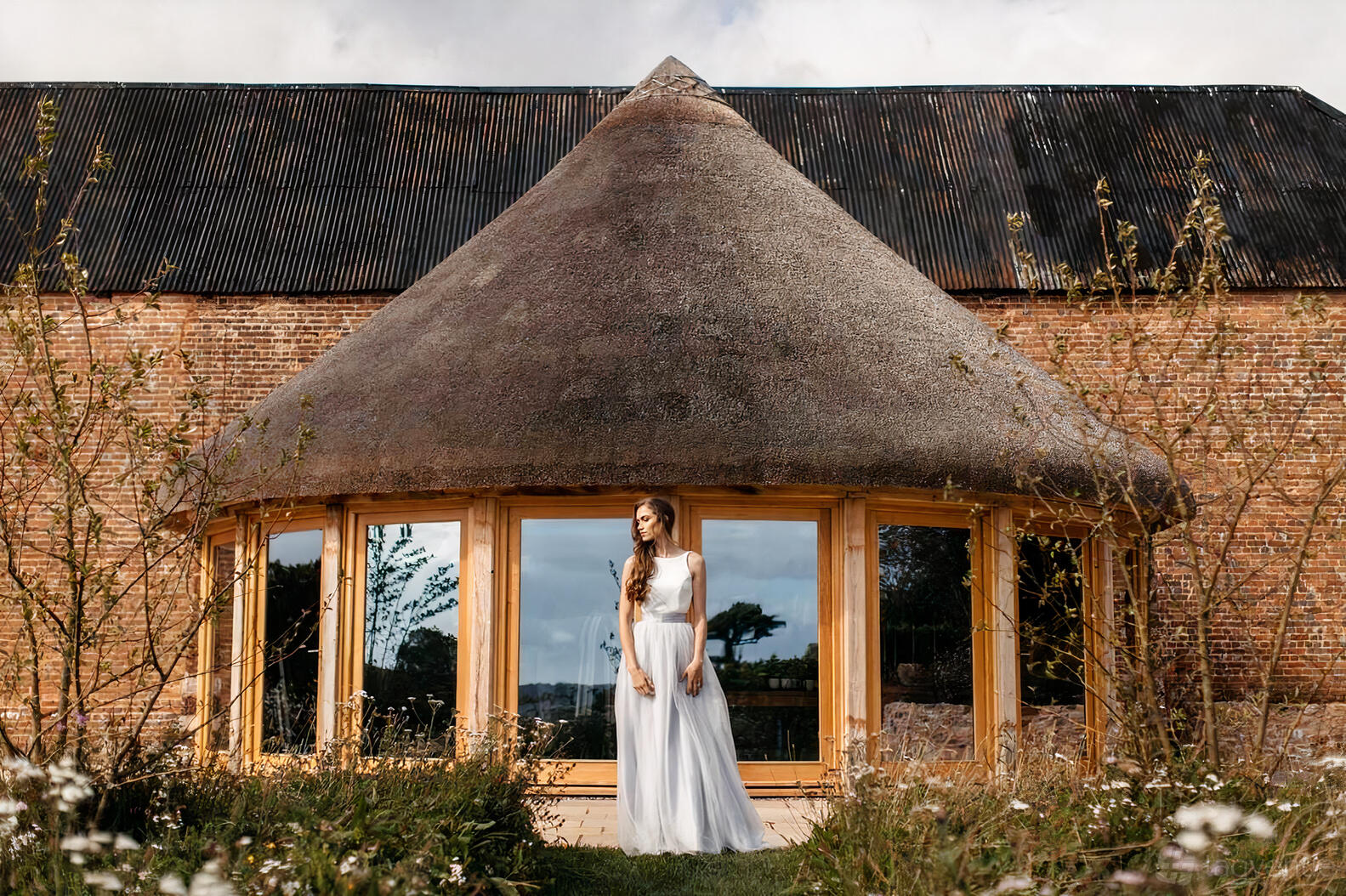 An event venue with a thatched roof, rounded windows, and brick exterior at Brickhouse Vineyard.