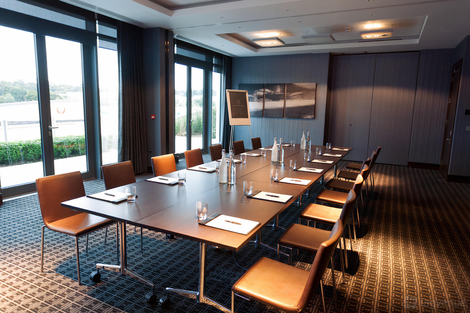 A conference room with floor-to-ceiling windows, long meeting table, and leather chairs at Brooklands Hotel.