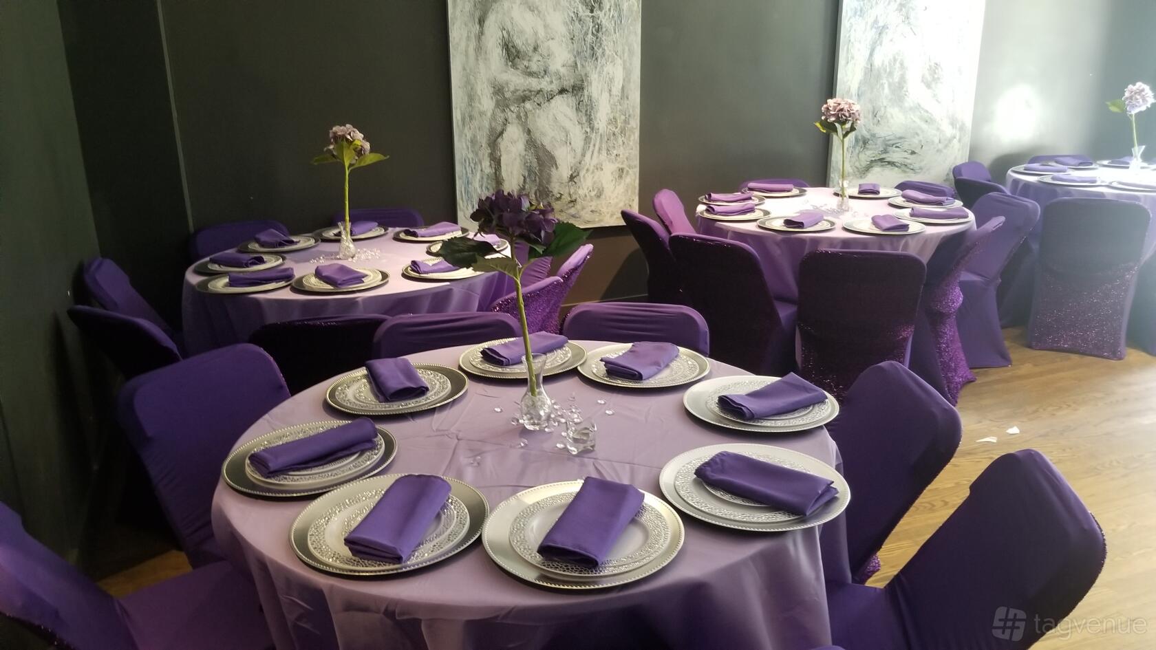 An event space with round tables draped in purple linens and coordinated napkins at Home to Harlem.