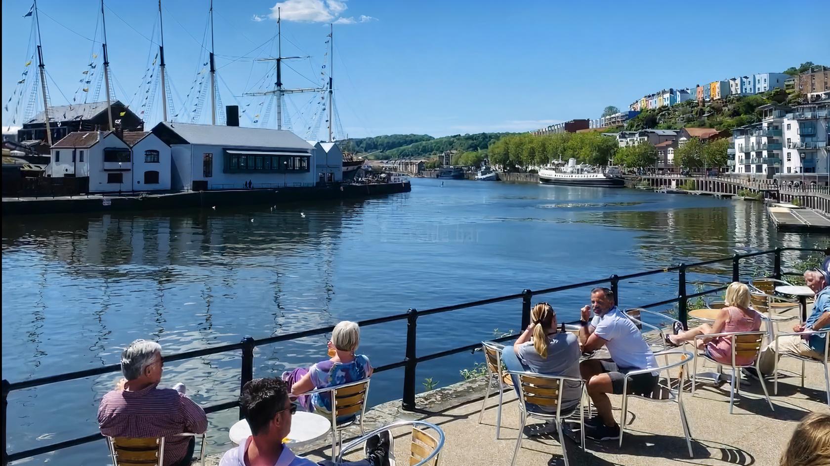 A restaurant terrace with outdoor tables overlooking the harbor and colorful houses at Brown & Bye.