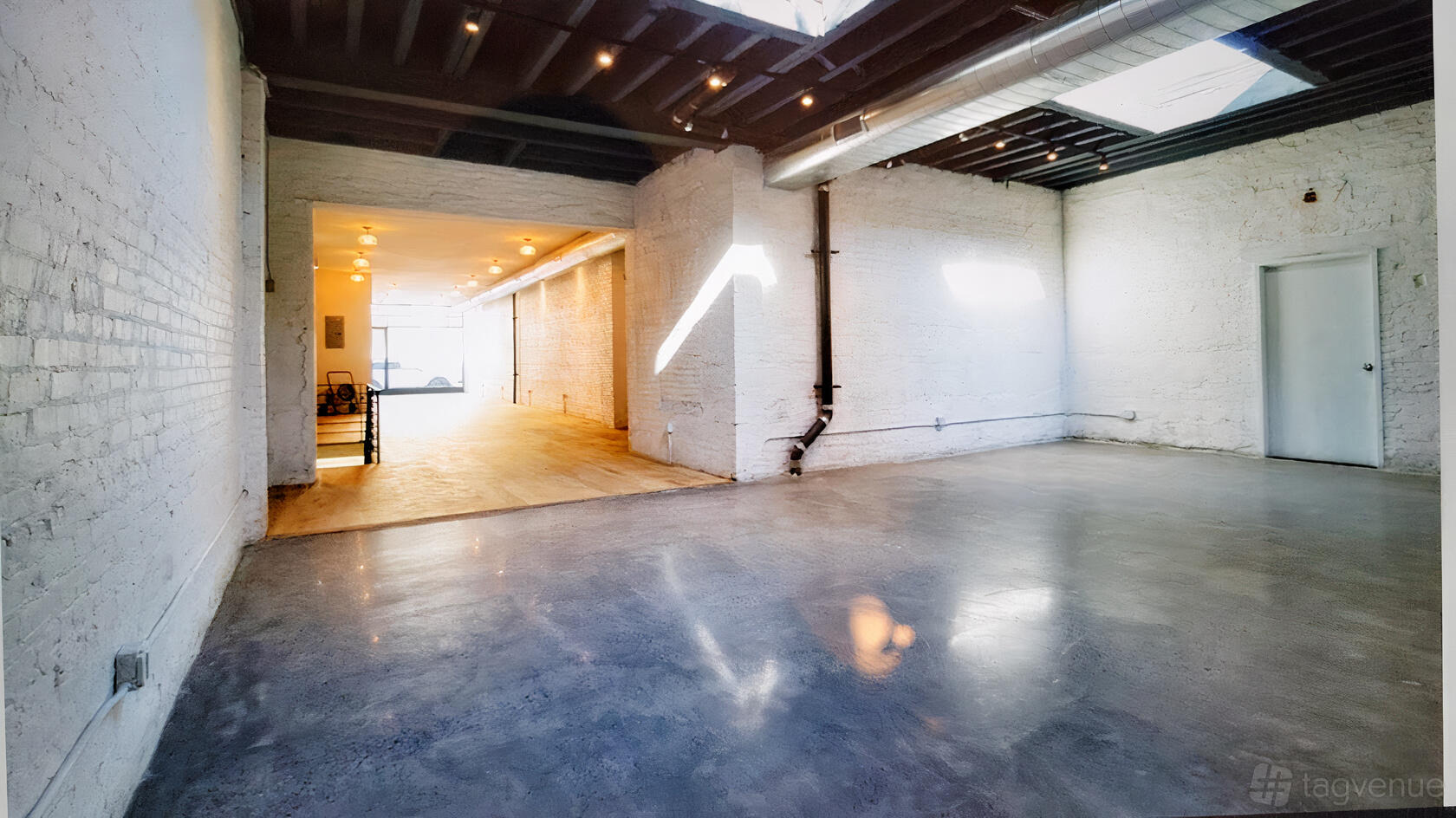 A hall with polished concrete floors, exposed brick walls, and skylights at Garden House NYC.