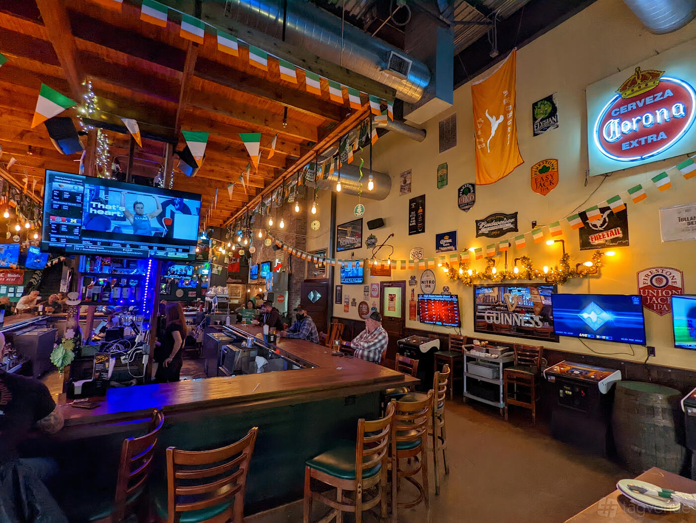 A pub with a long wooden bar, string lights, TVs, and festive banners at Mo's Irish Pub Cypress.