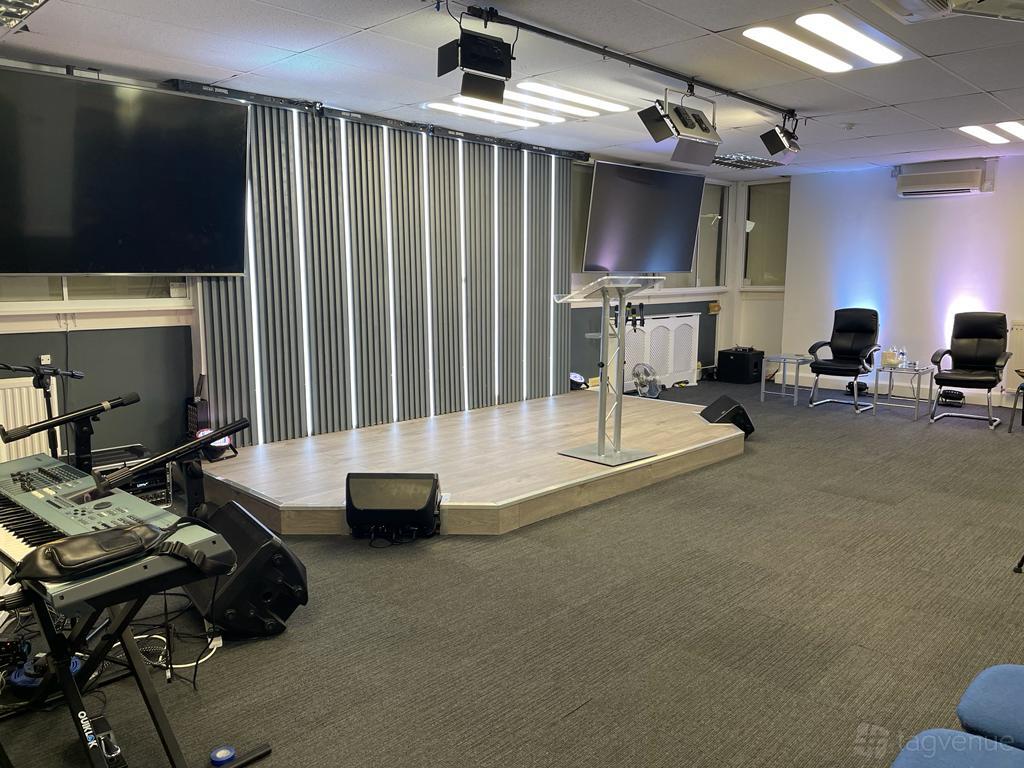 An auditorium with a raised stage, lectern, wall-mounted screens, and conference seating at Life Centre.