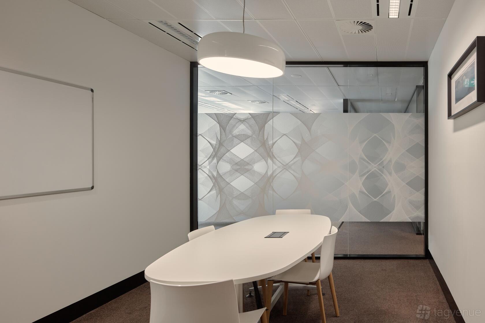 A meeting room with a white oval table, four chairs, glass wall with patterned frosting, and a whiteboard at Flex by ISPT at 4 National Circuit.