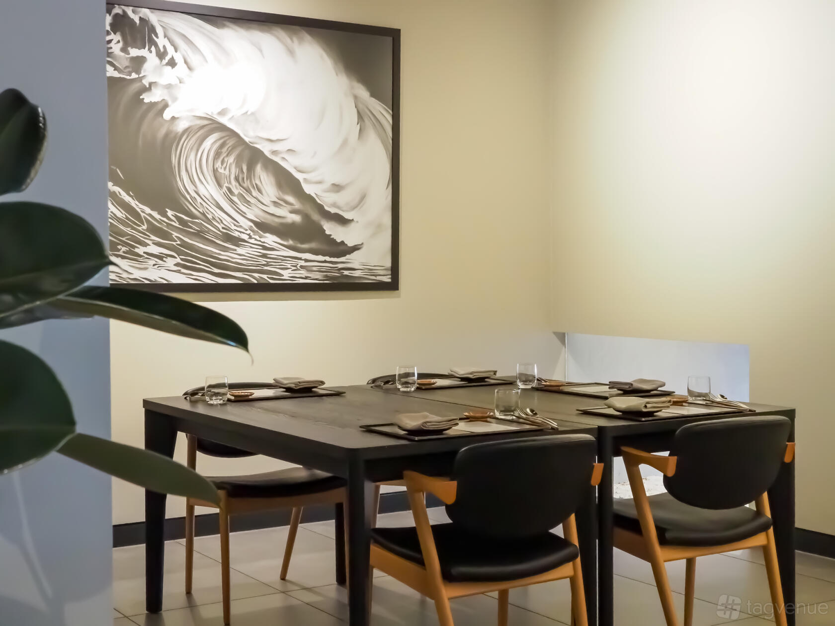 A private dining room with a black table set for six, minimalist decor, and a wave mural at KOMEYUI Melbourne.