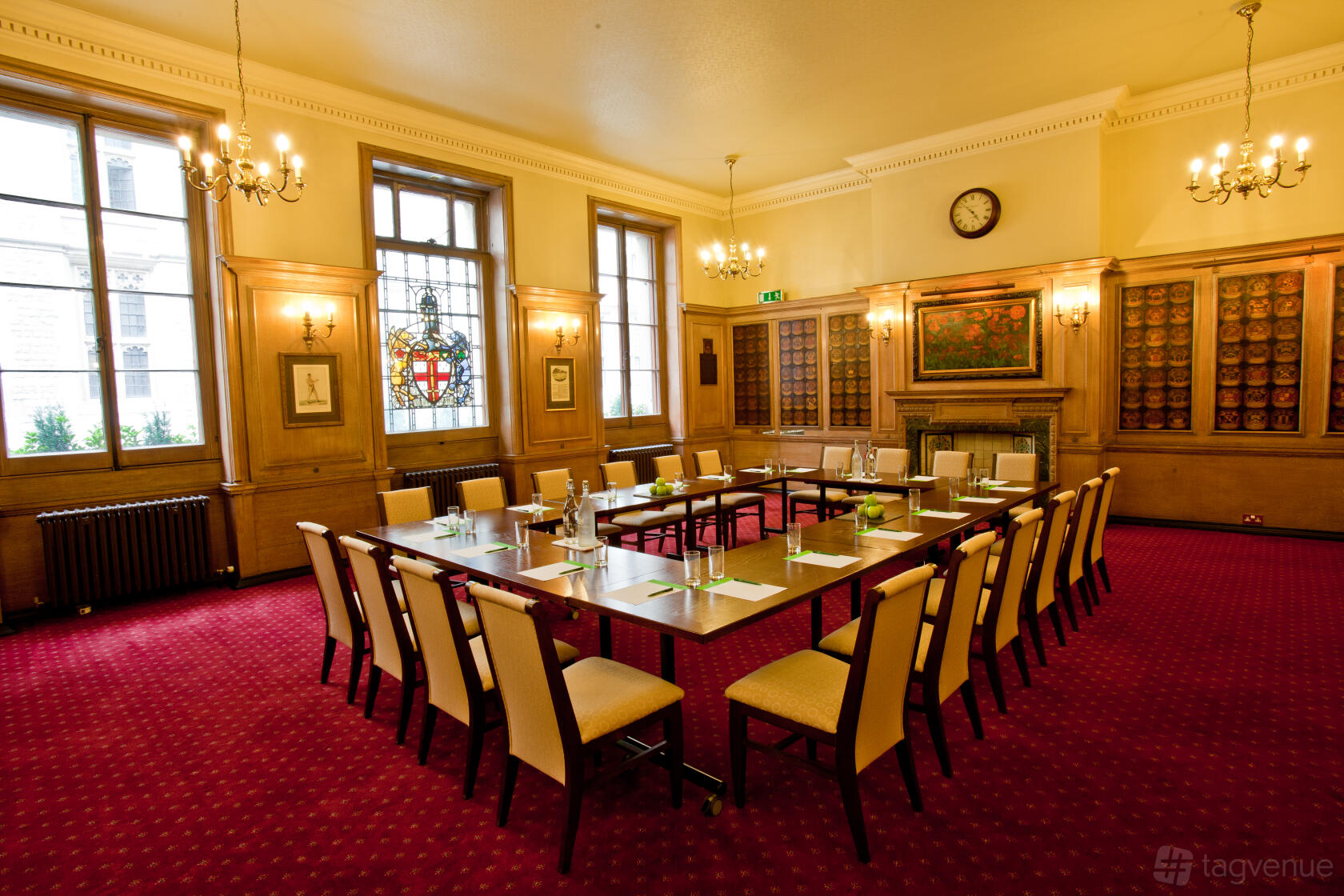A function room with wood paneling, tall windows, a U-shaped table, and red carpet at 113 Chancery Lane.
