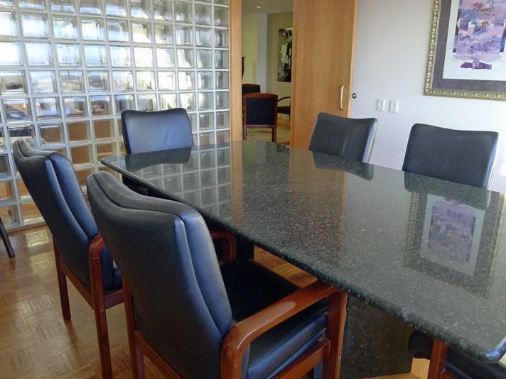 A meeting centre with a granite conference table, black leather chairs, and a glass block wall at Northbrook Office Rentals.
