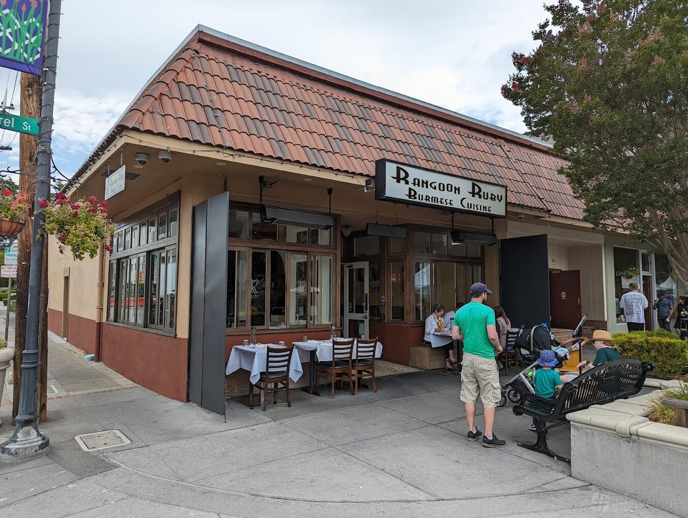 A restaurant with outdoor sidewalk seating, large windows, and a brown tile roof at Rangoon Ruby Burmese Cuisine.