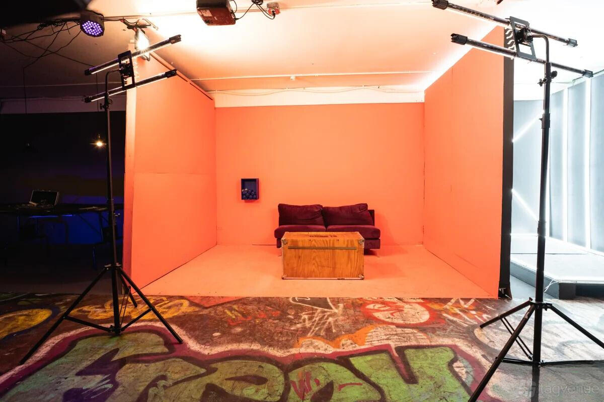 A photo studio with a coral-colored set, purple sofa, and soft overhead lighting at Kreative Cave.