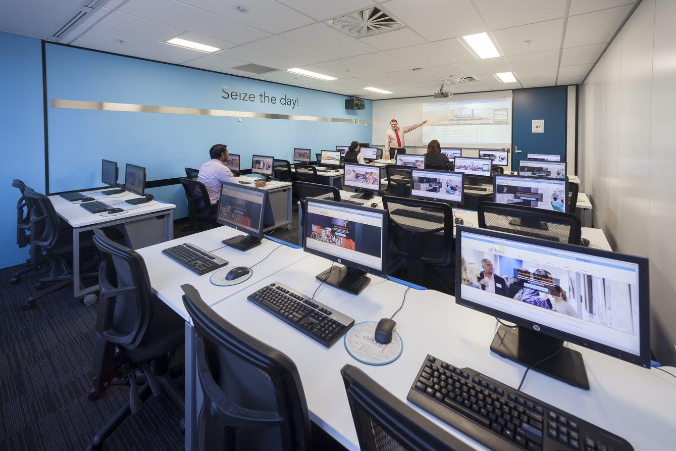 An event venue with rows of computer stations, large monitors, and a projector wall at Cliftons Melbourne - Collins St.